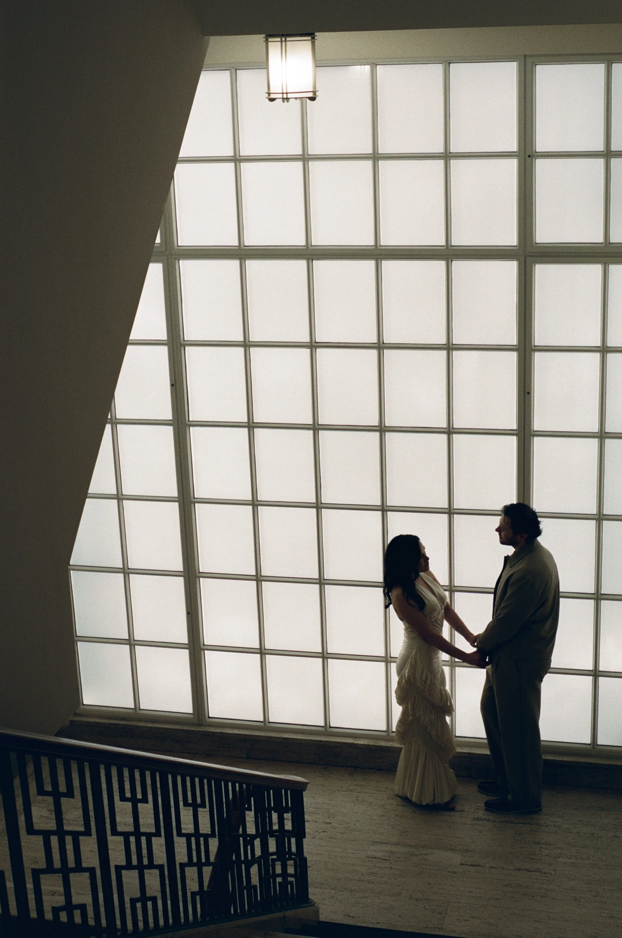  Rachel and Dakota walking together inside the Portland Art Museum on a rainy November day, modern and intimate engagement session, shot on film 