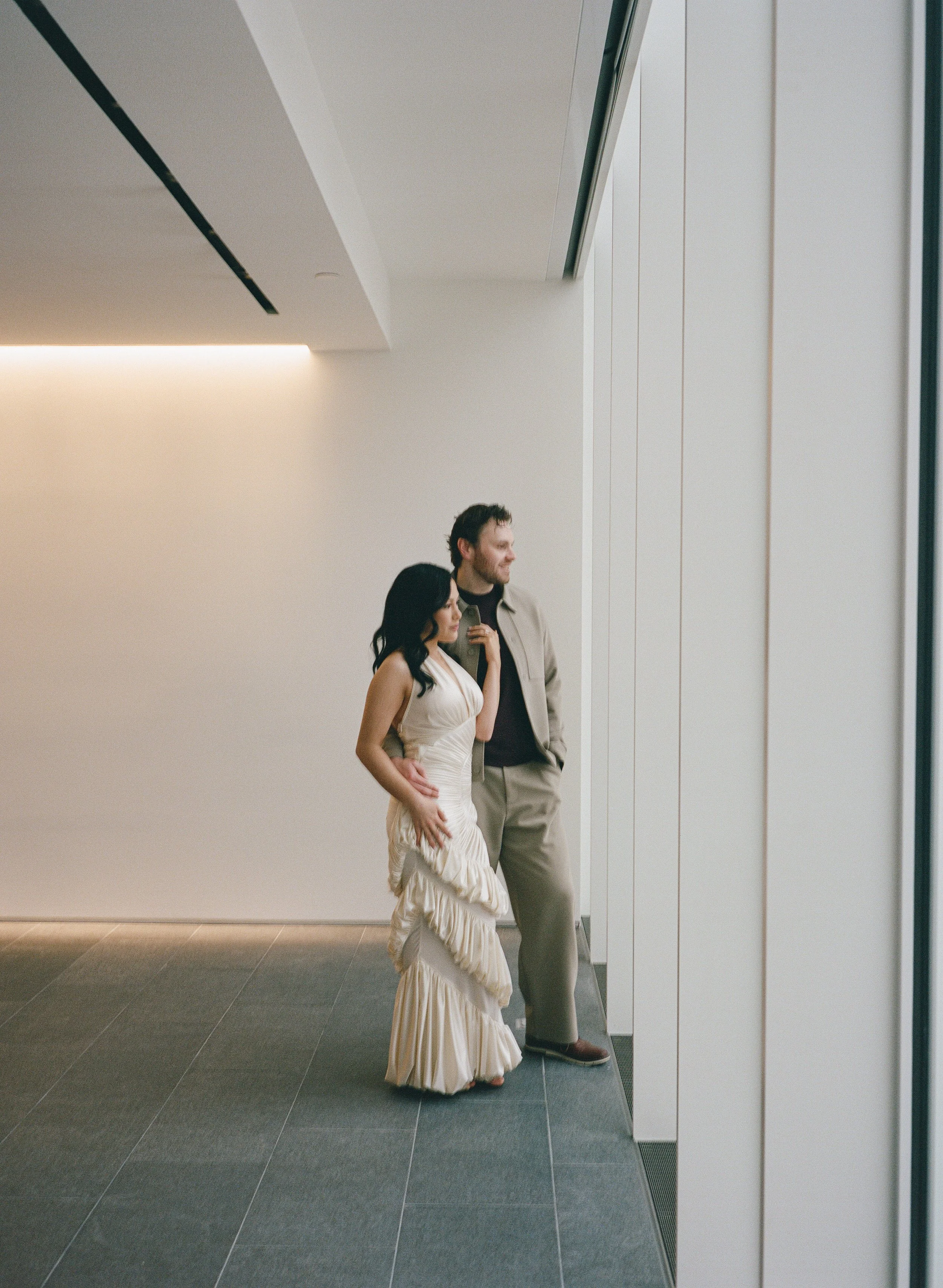  Rachel and Dakota walking together inside the Portland Art Museum on a rainy November day, modern and intimate engagement session, shot on film 
