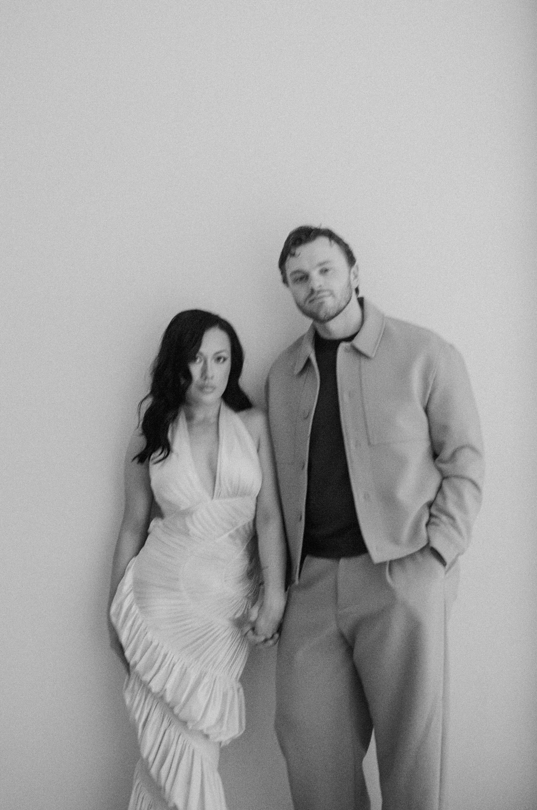  Rachel and Dakota standing closely in the Portland Art Museum with minimalist architecture behind them, artistic engagement photos in Portland, shot on film 