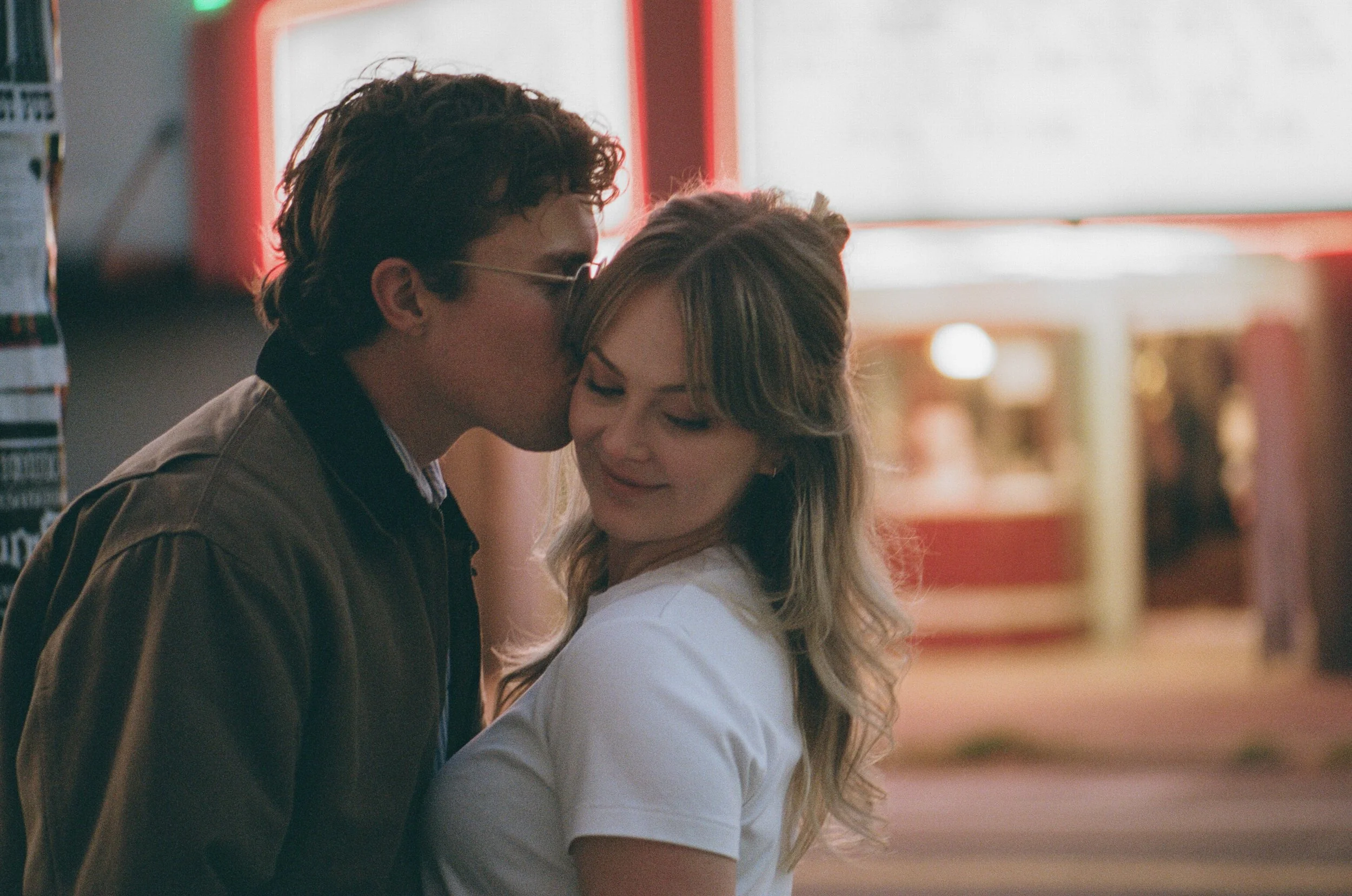  couple outside Laurelhurst Theater Portland under neon marquee lights at night, cinematic engagement photo shot on 35mm film 