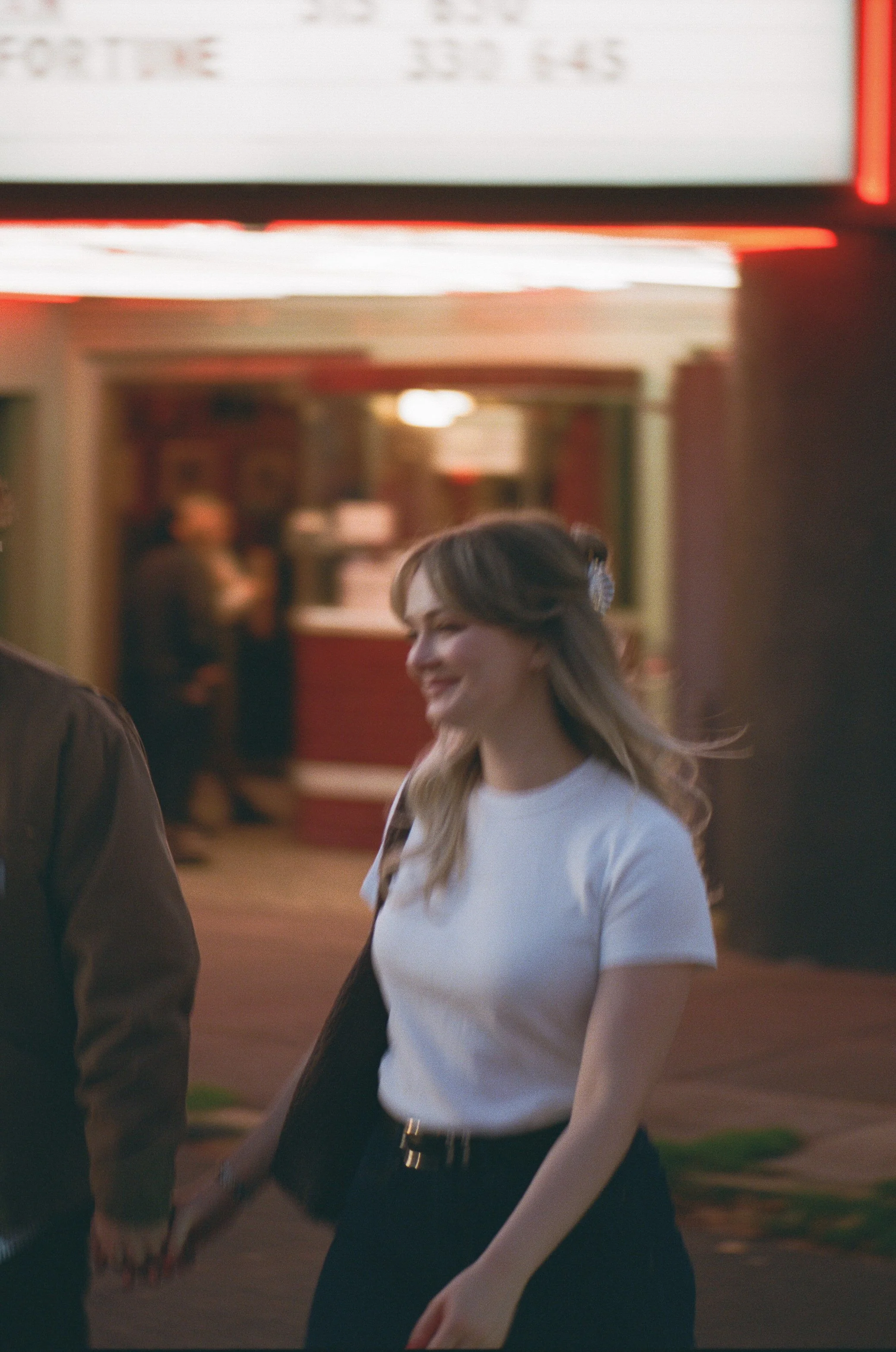  couple outside Laurelhurst Theater Portland under neon marquee lights at night, cinematic engagement photo shot on 35mm film 