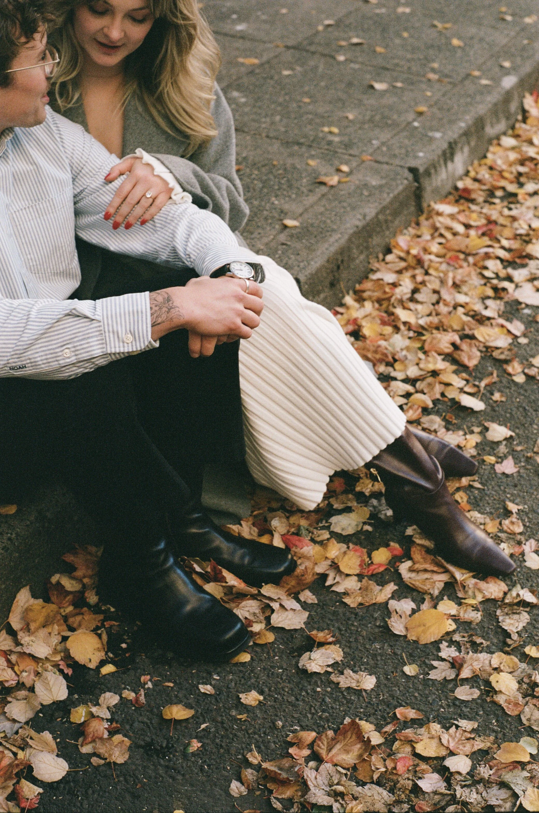  couple walking through downtown Portland in autumn with golden leaves and modern architecture, candid engagement photography 