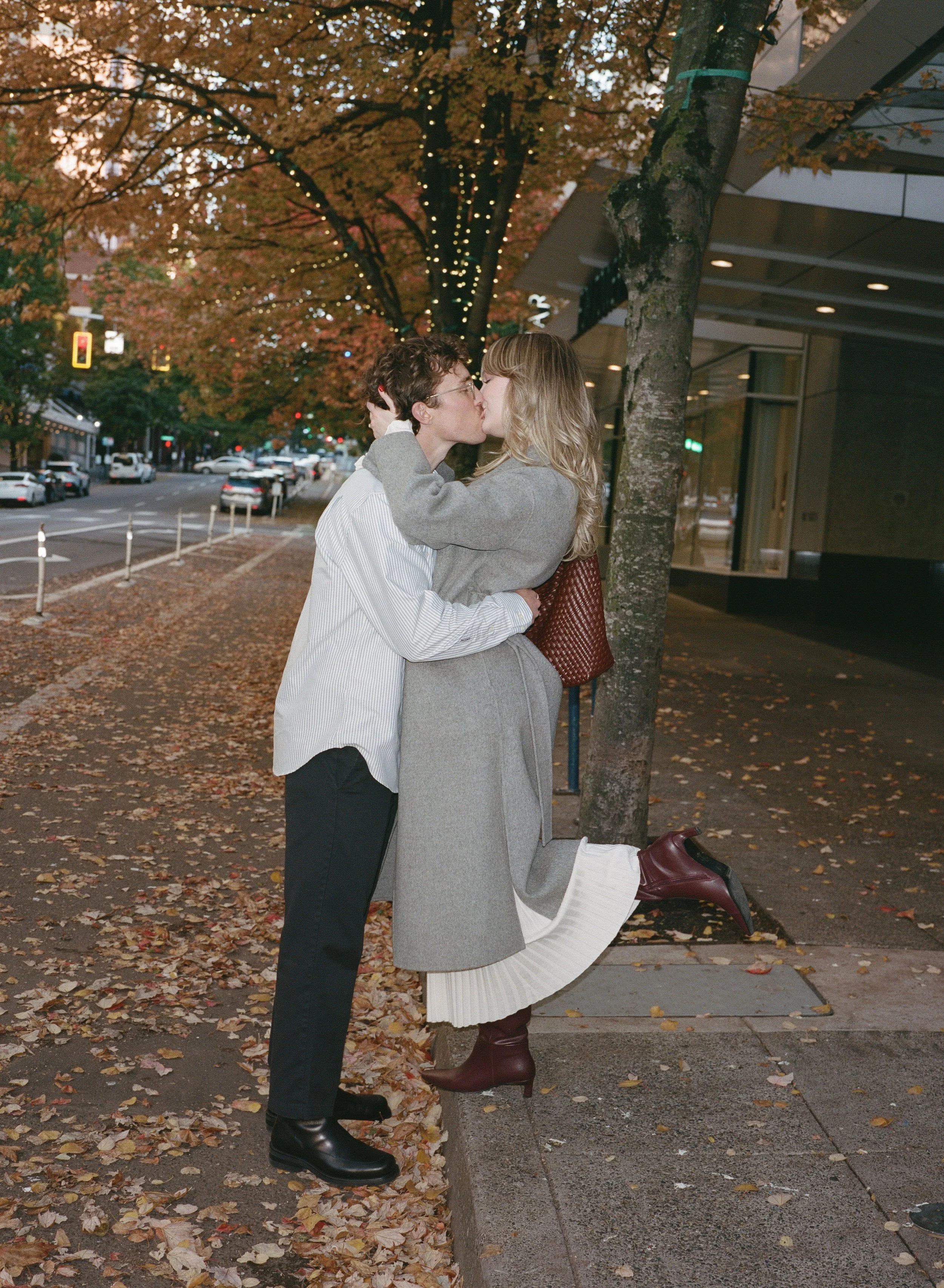  couple walking through downtown Portland in autumn with golden leaves and modern architecture, candid engagement photography 