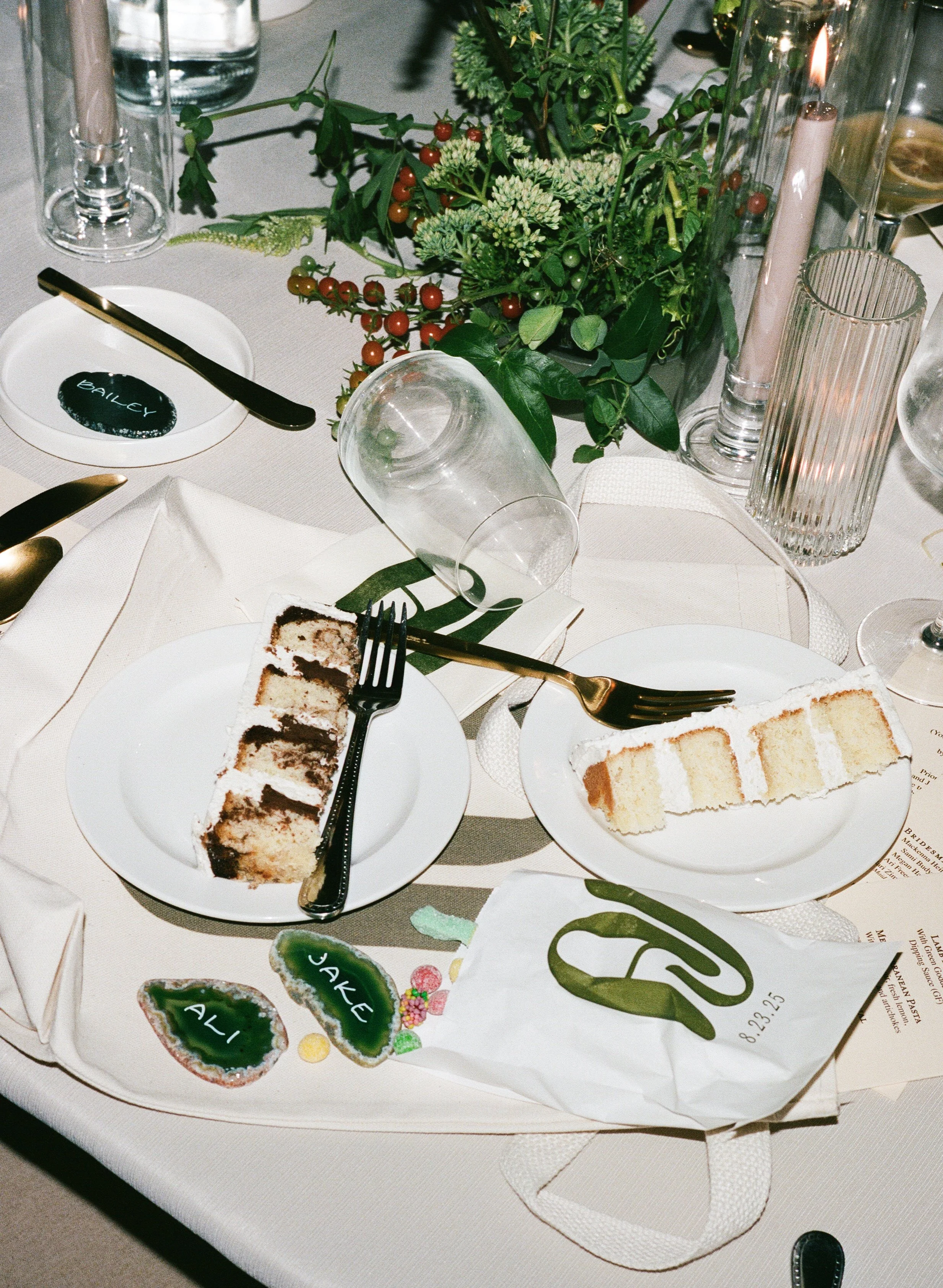  120mm film detail shot of reception tablescape with colorful floral arrangements and cake / messy late night flat lay 