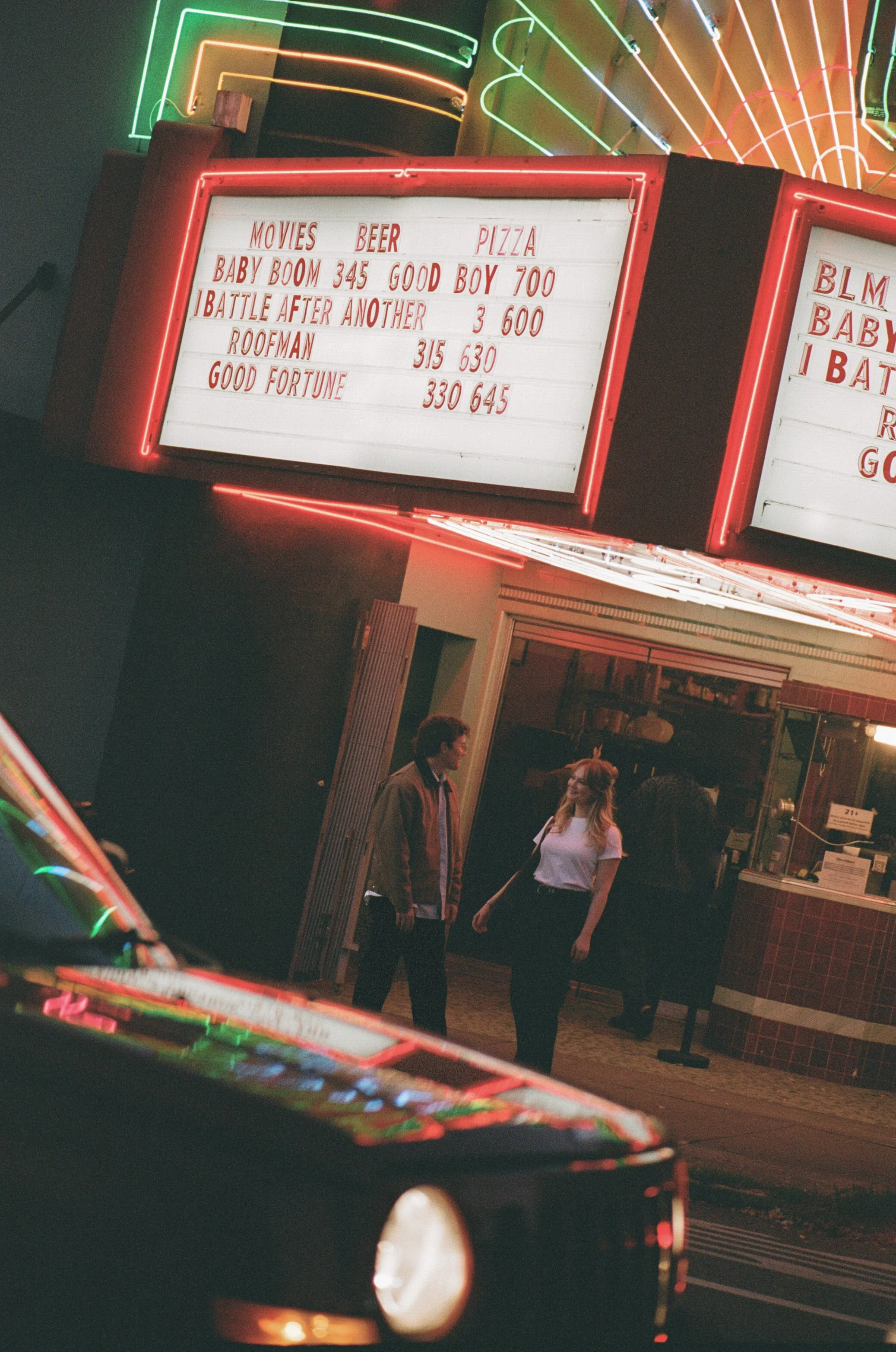 couple outside Laurelhurst Theater Portland under neon marquee lights at night, cinematic engagement photo