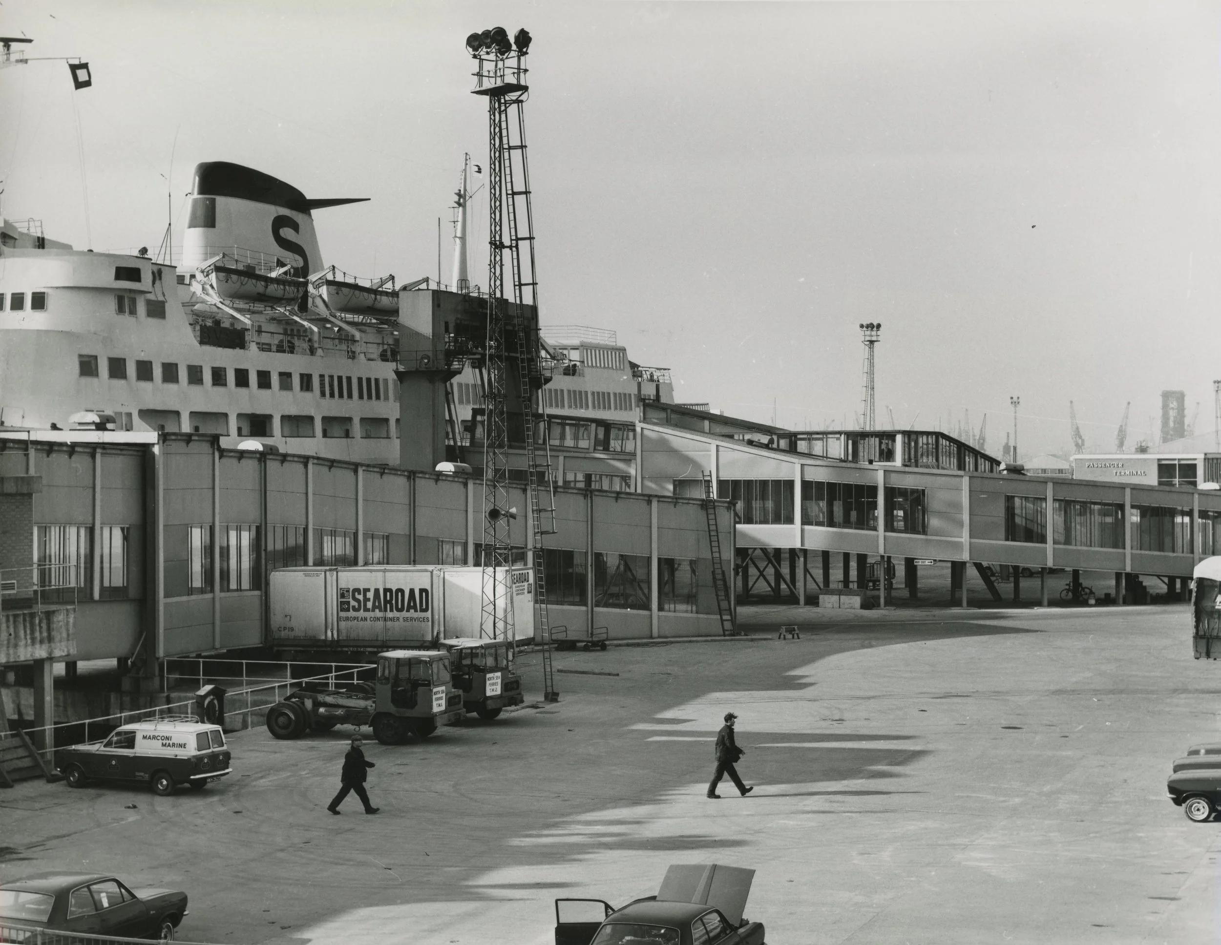 Two men strolling across the car park at The Ferry Terminal. King George Dock, Hull. 1st February, 1967. Photographer - Donald I. Innes Commissioned by ABP.