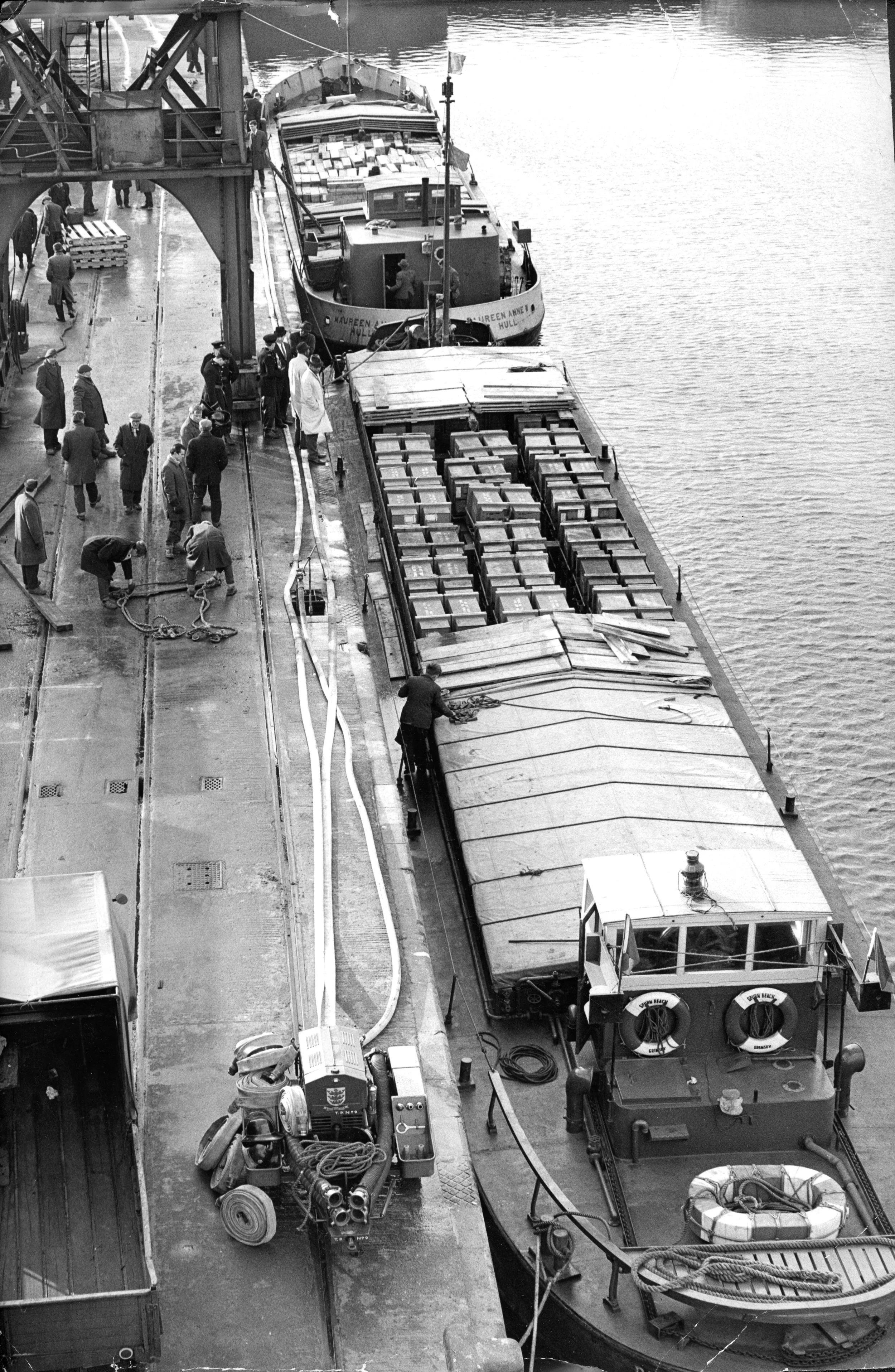 Ammunition barges unload-dockers beginning to unload 250 tons of ammunition from barges at an isolated berth in William Wright dock, Hull. The ammunition is from the US Air Force bases in France. Firemen were standing by as a routine caution, 1960’s. Commissioned by Hull Daily Mail.