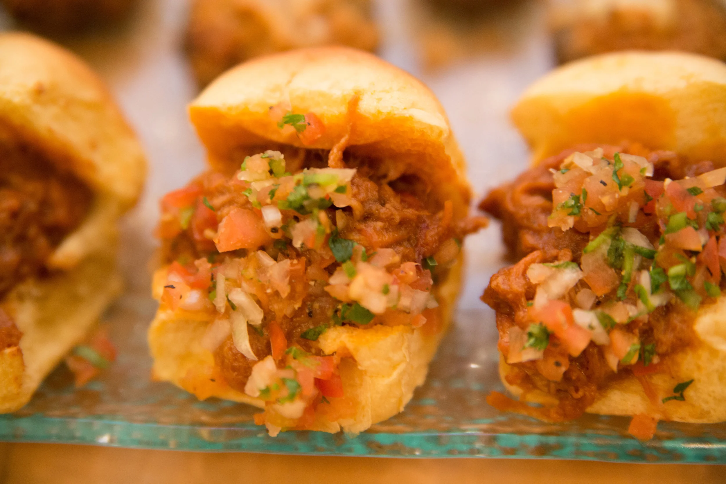 Close-up of three Mexican street tacos filled with seasoned ground beef, diced tomatoes, onions, cilantro, and topped with chopped herbs on soft yellow corn tortillas.