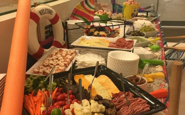 Buffet table with various breakfast foods including cheese, meats, fruit, and sides at a party or gathering.
