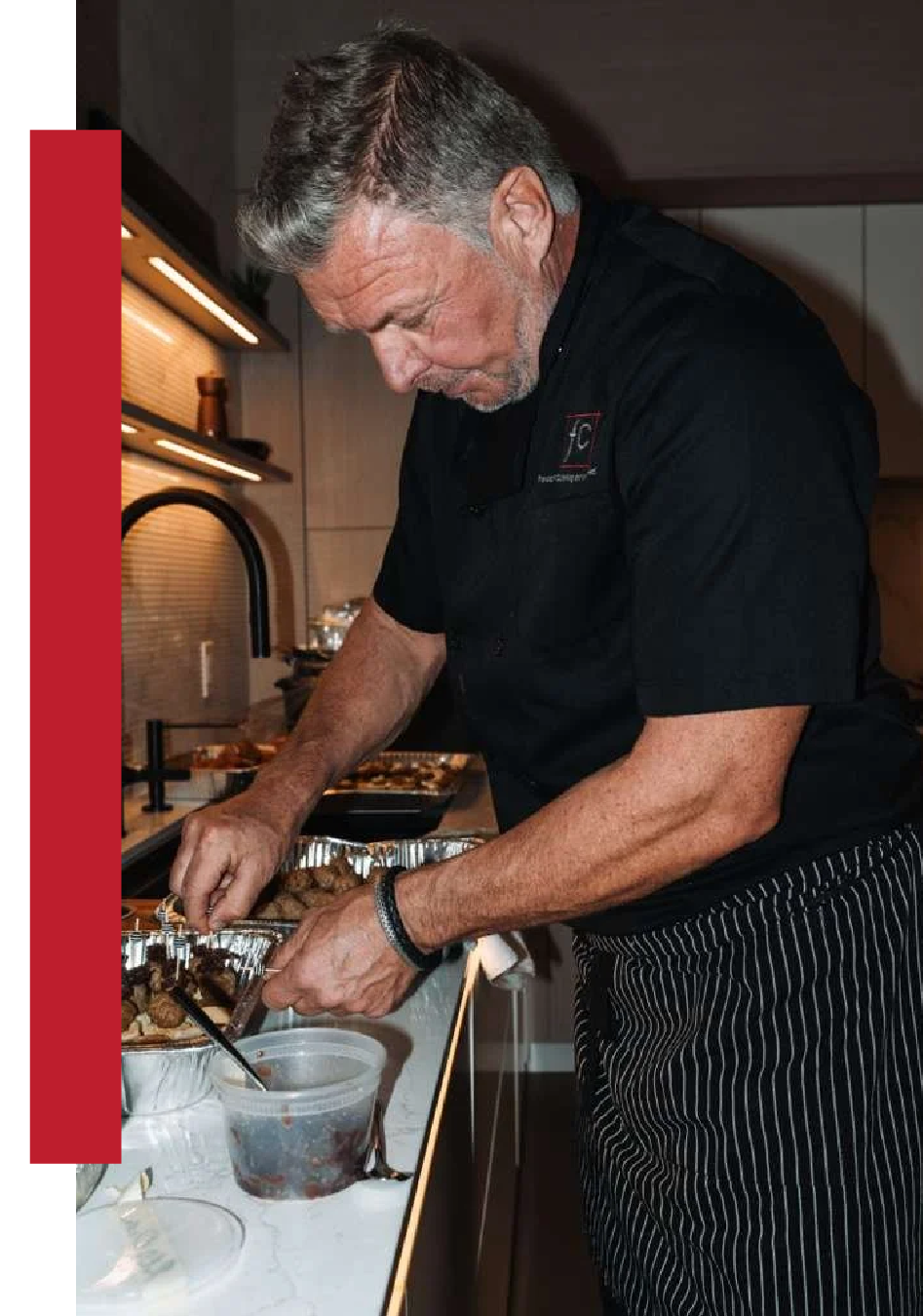 Man in a black chef's uniform preparing food in a modern kitchen.