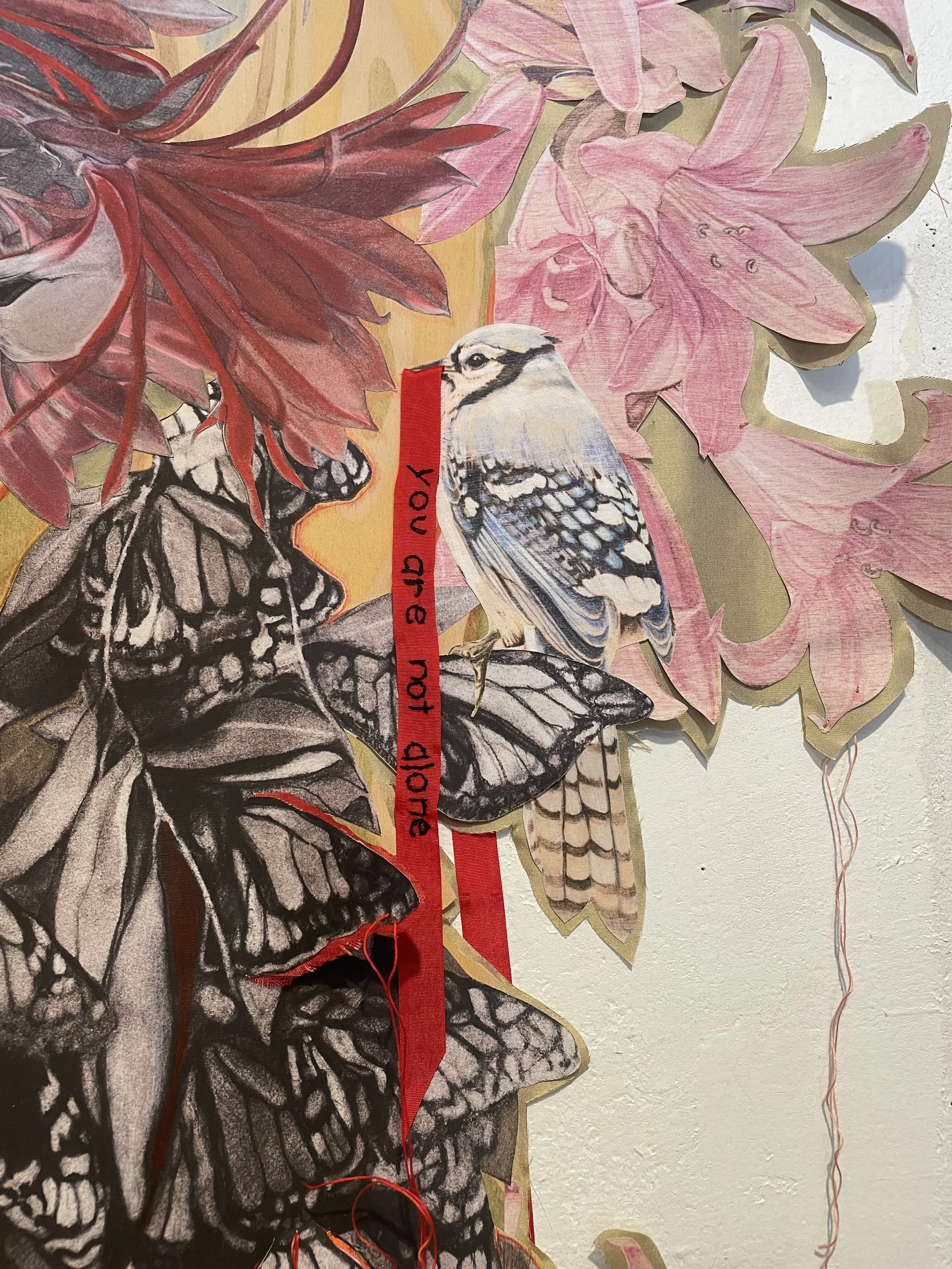 Detail featuring monarch butterflies, a bird, and floral elements with a red ribbon that has handwritten text, against a background of pink flowers and yellow foliage.