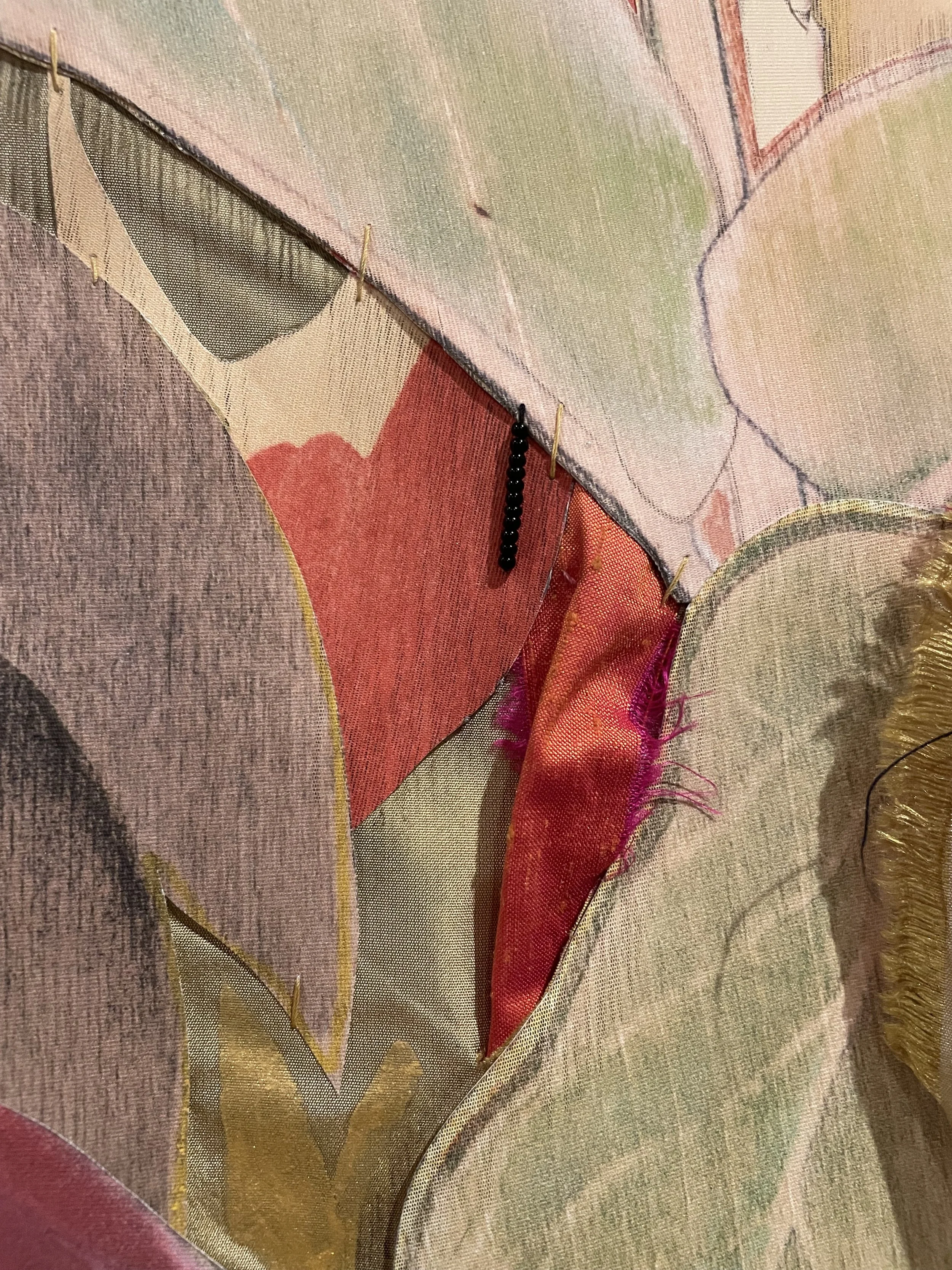 Detail of "The Return" featuring layered fabrics with pins and a small beaded chain.
