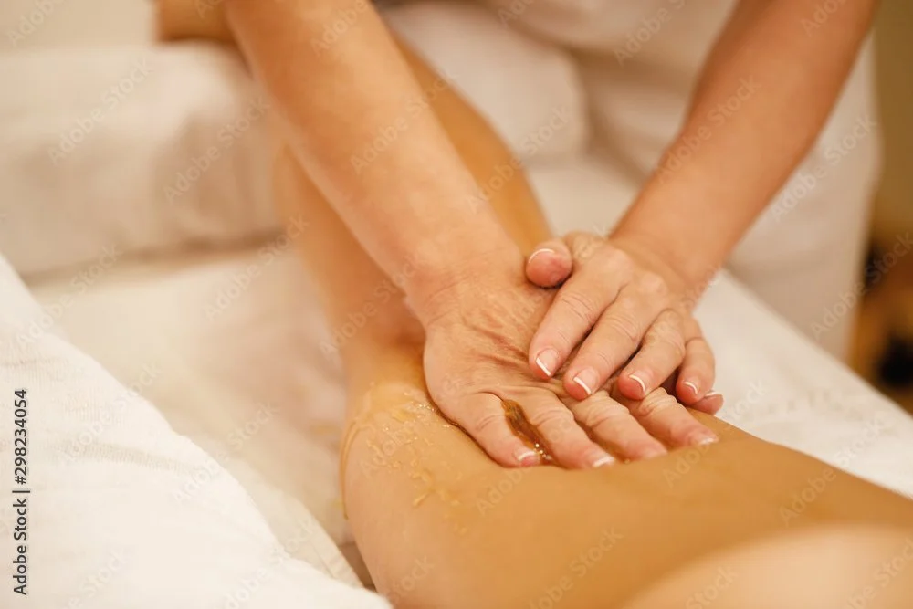 Person receiving a massage on their leg with oil applied.
