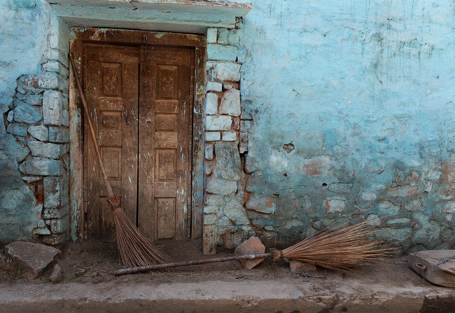 Door, wall and two brooms, Nandgaon, India