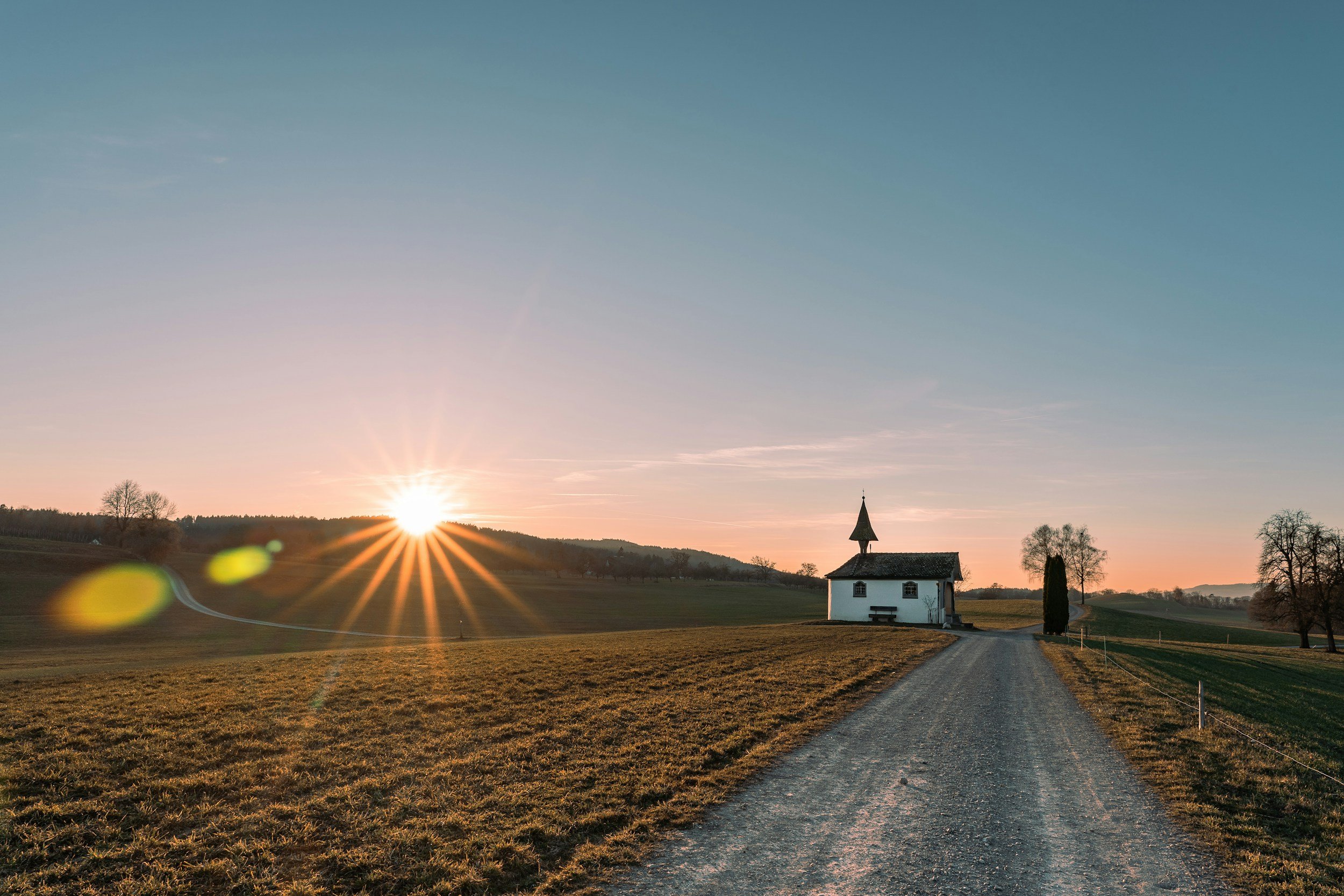 Sunrise in a rural area, a path, and a house.