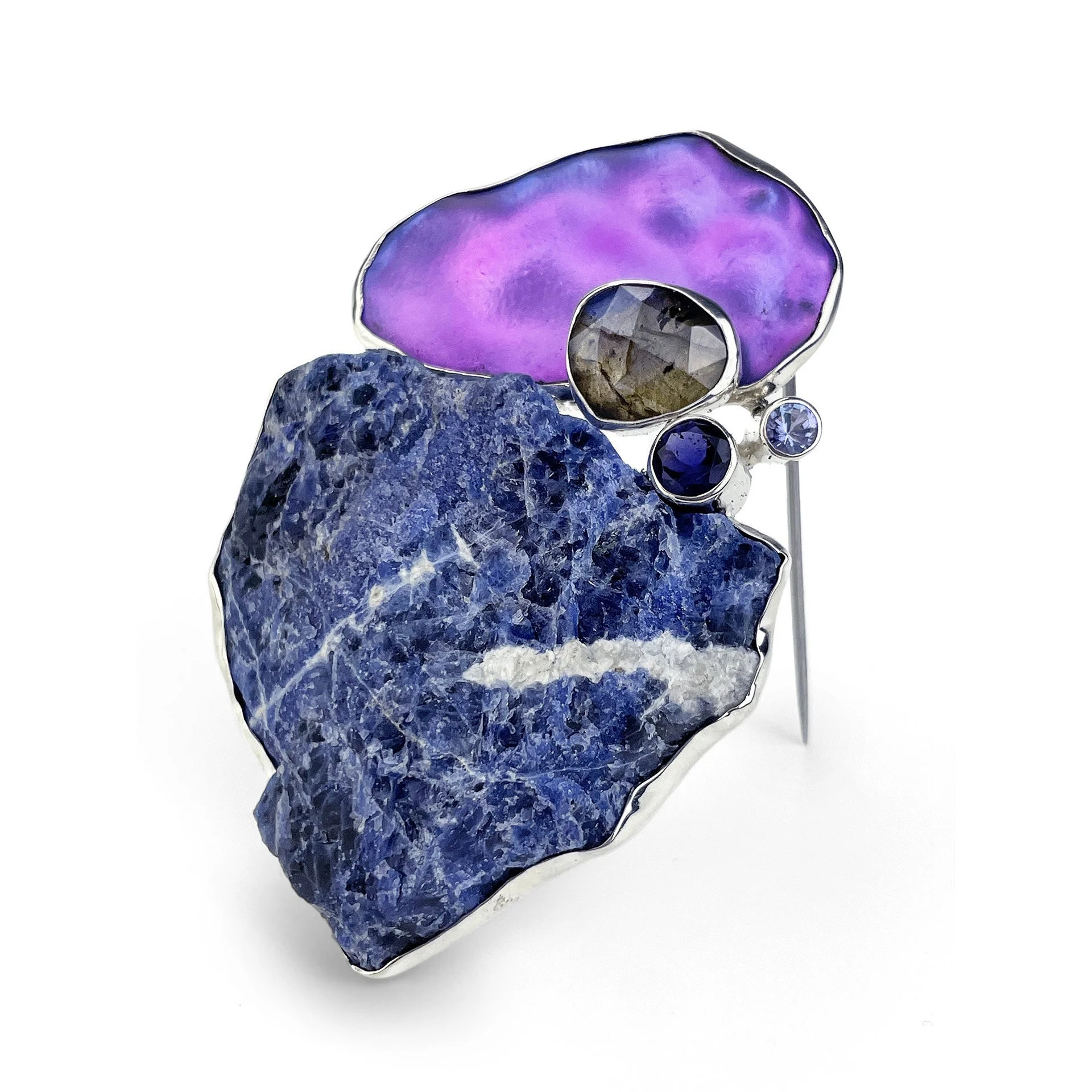 A statement brooch made of sodalite, labradorite, , iolite, tanzanite, and cold-worked glass that can also be worn as a pendant.
