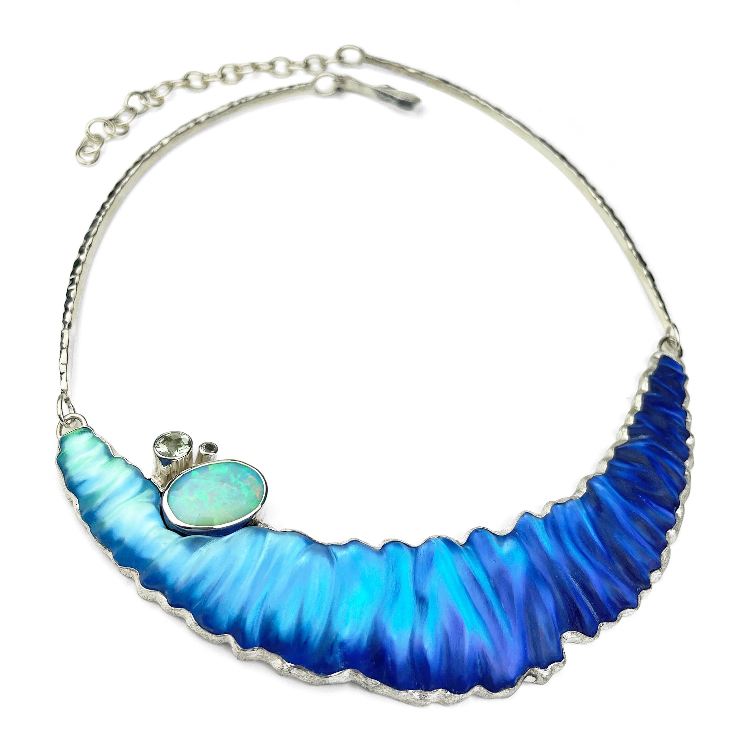 A statement necklace made of hand carved sterling silver, hand carved glass, genuine opal and green amethyst that isnspired by the ocean.
