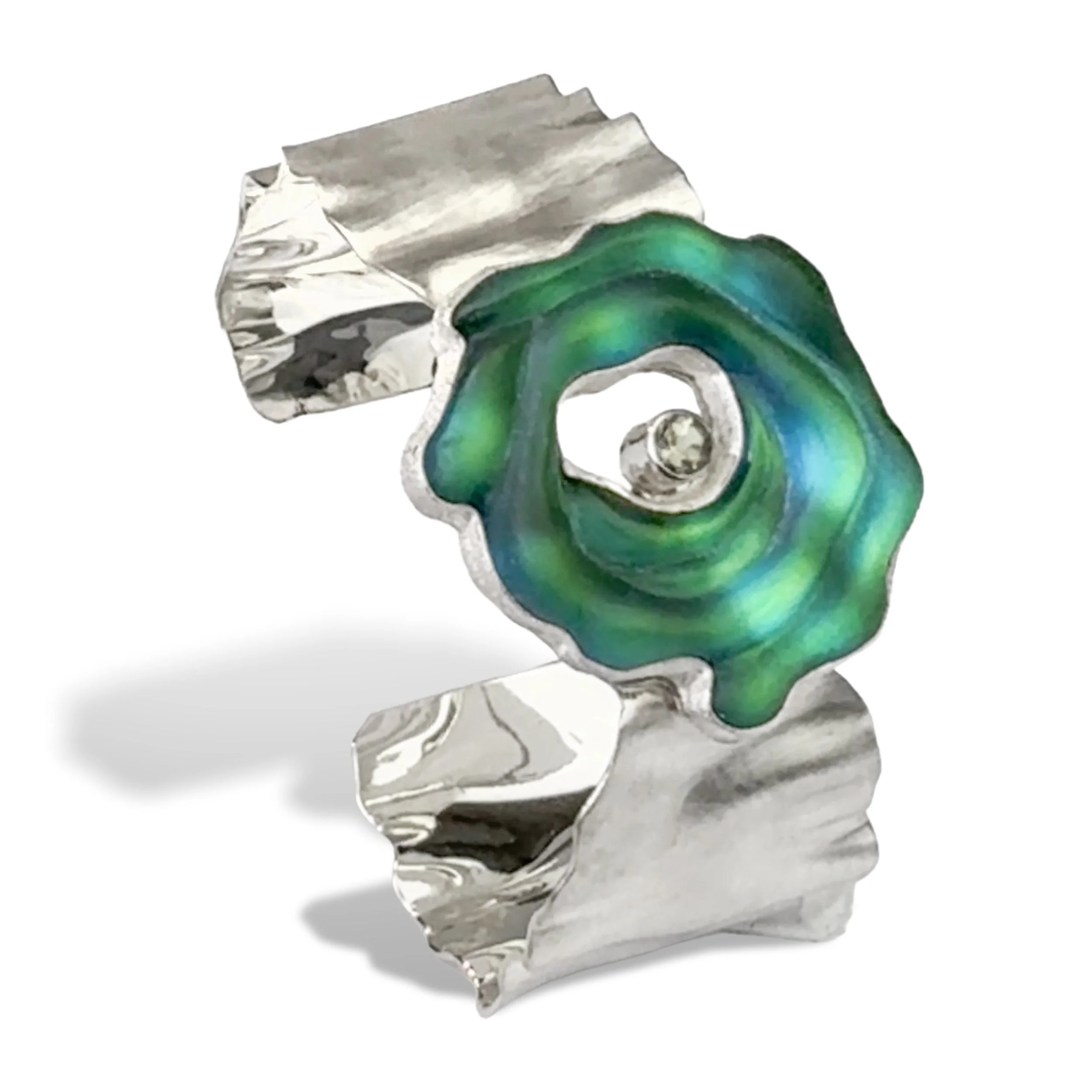 Sterling silver cuff with a hammered, crumpled texture holding a swirling green glass element and a white gemstone.