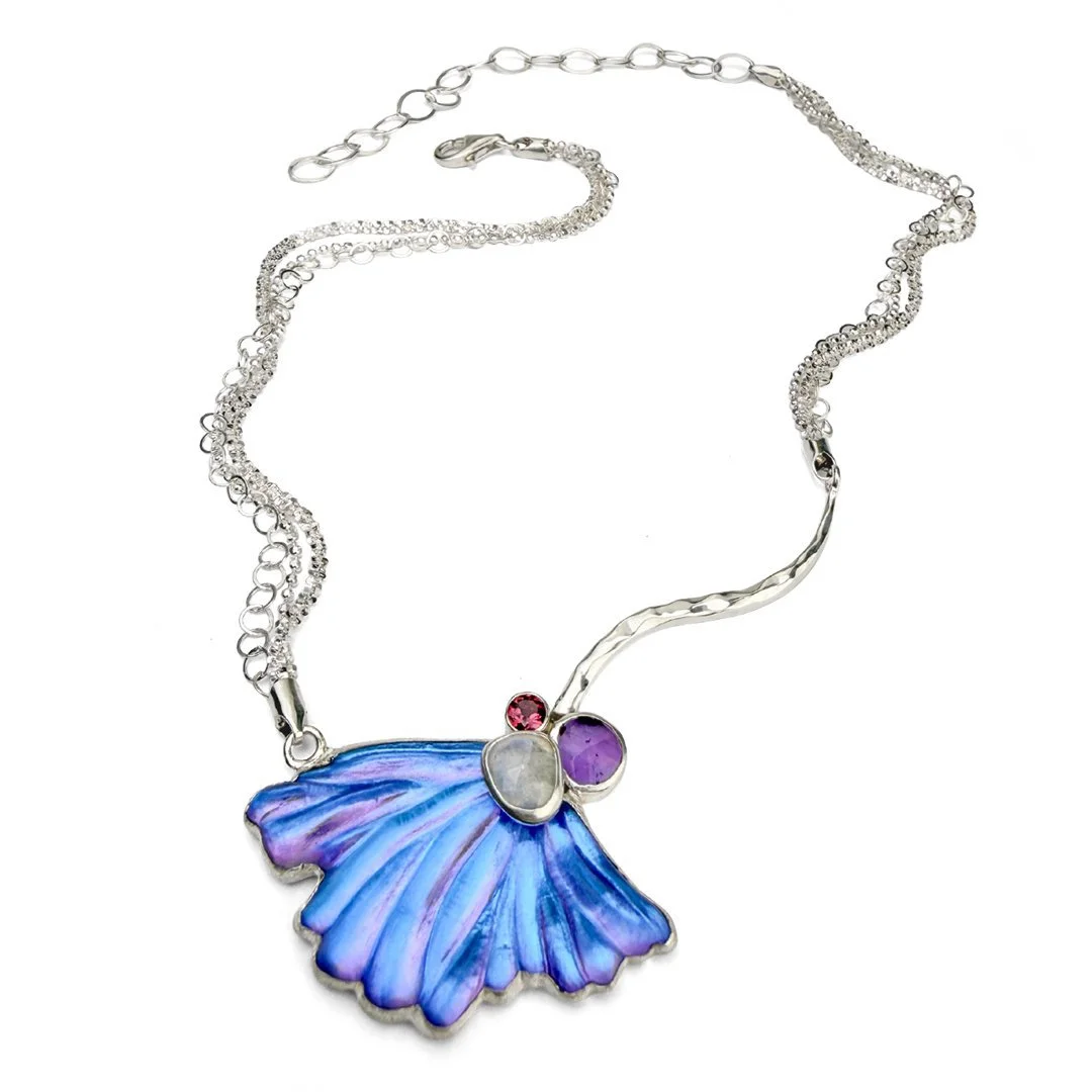 Silver necklace with a blue, purple, and red gemstone and a butterfly-shaped pendant with an iridescent blue wing.