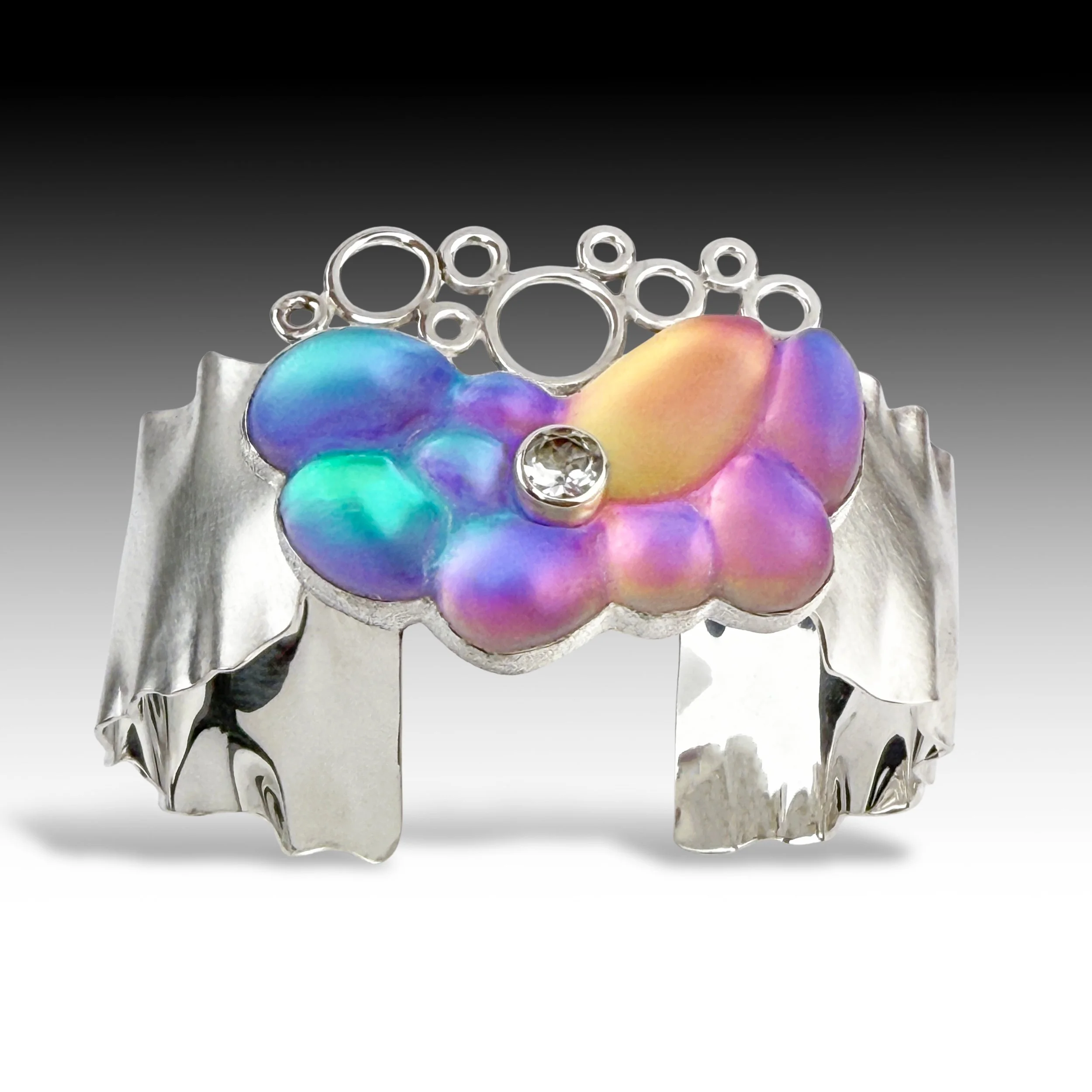 A contemporary cuff bracelet made of carved glass, sterling silver, and white topaz.