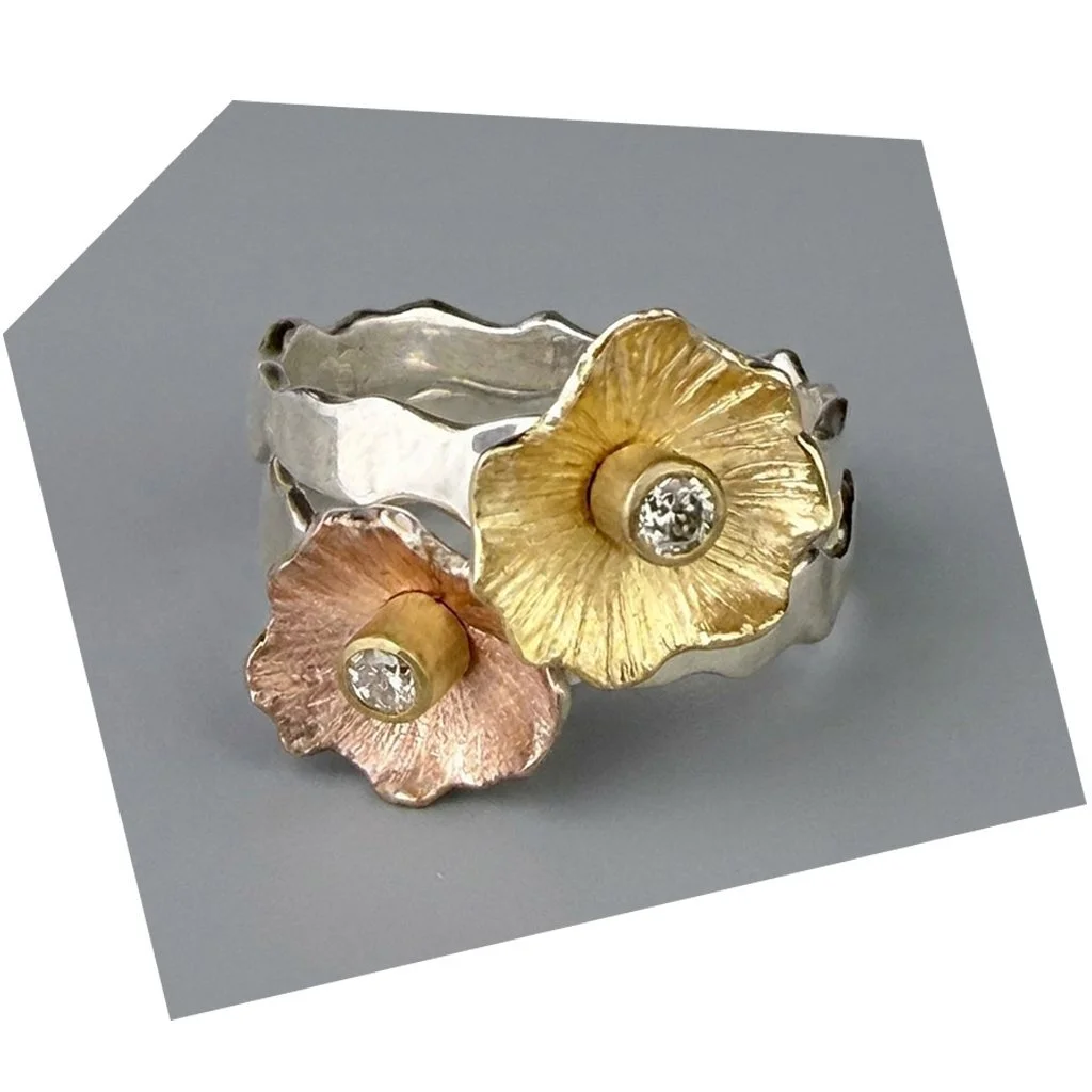 A ring featuring two flower designs, one gold and one rose gold, with diamond centers.