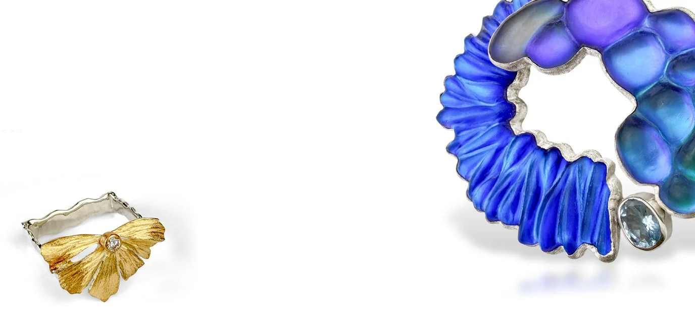 Close-up of gold and silver ring, next to a  decorative glass brooch with a iridescent blue and purple glass  and a natural blue topaz set in sterling silver.