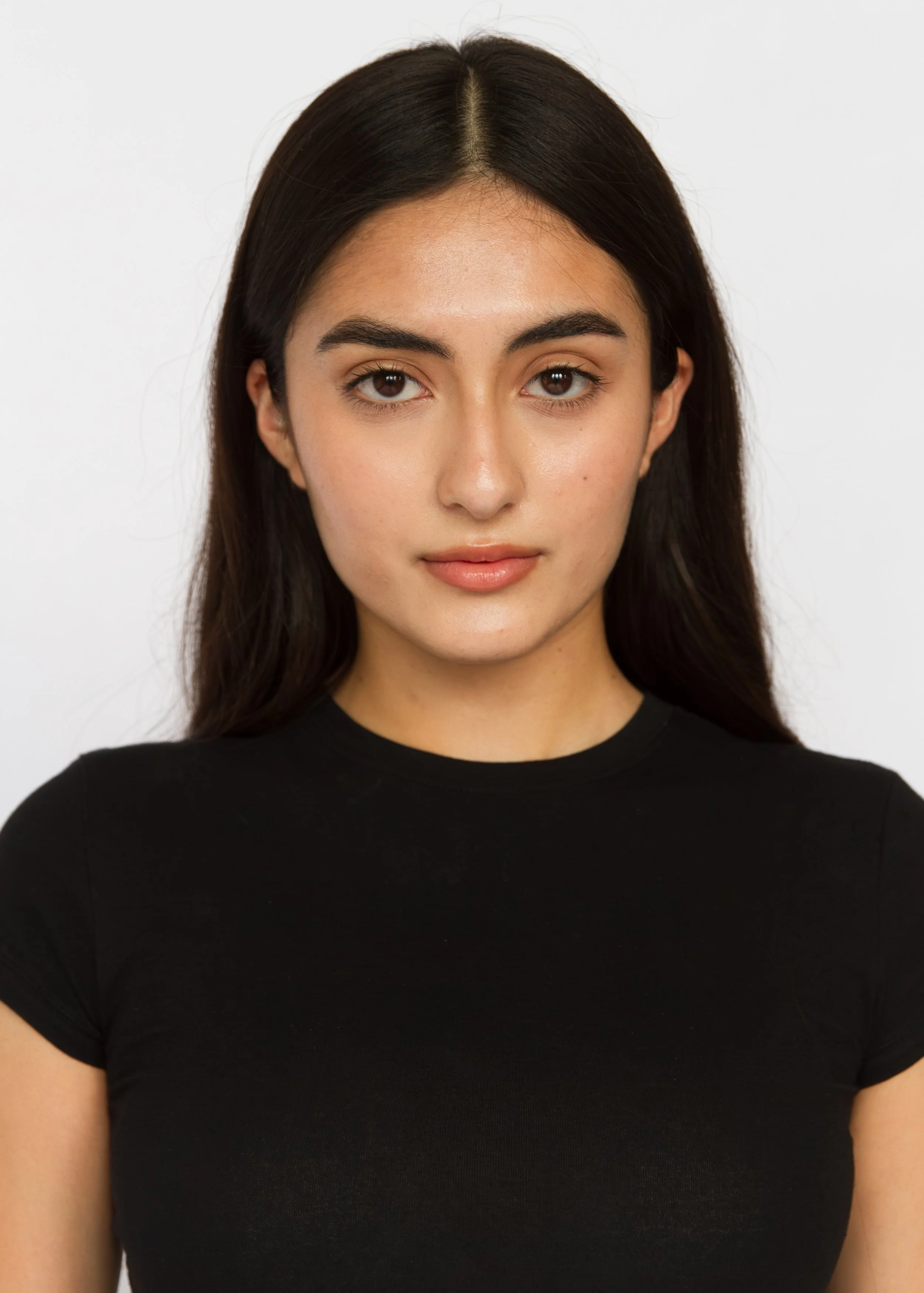 Close-up of a woman with dark hair and brown eyes, wearing a black shirt, against a plain white background. Model Digitals