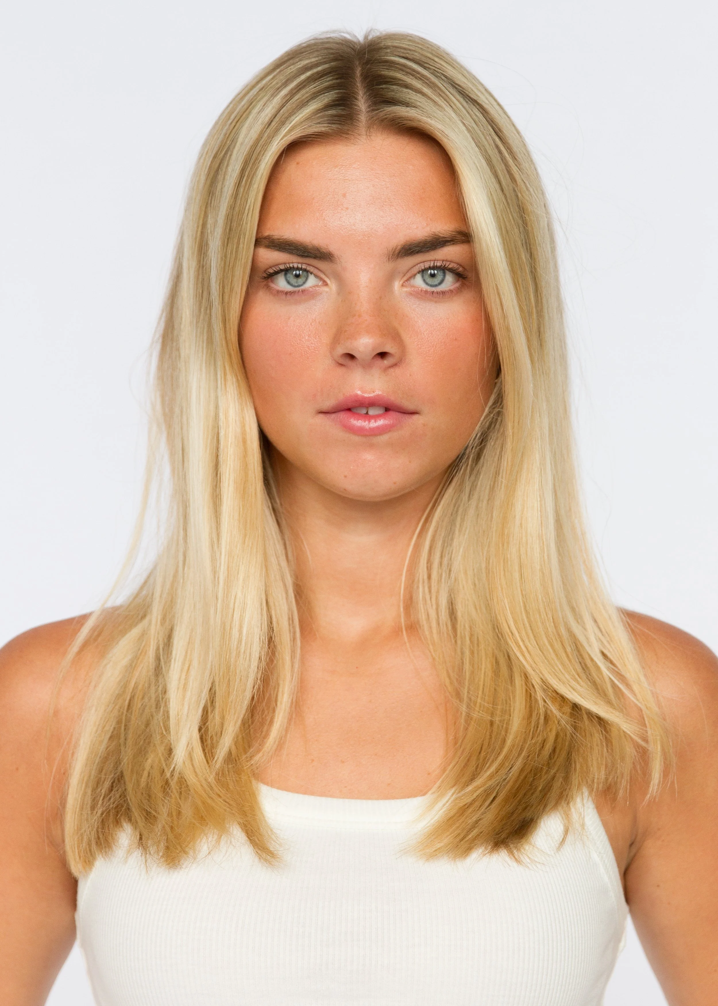 Close-up of a woman with long blonde hair, blue eyes, wearing a white tank top, against a plain white background. Model Digitals