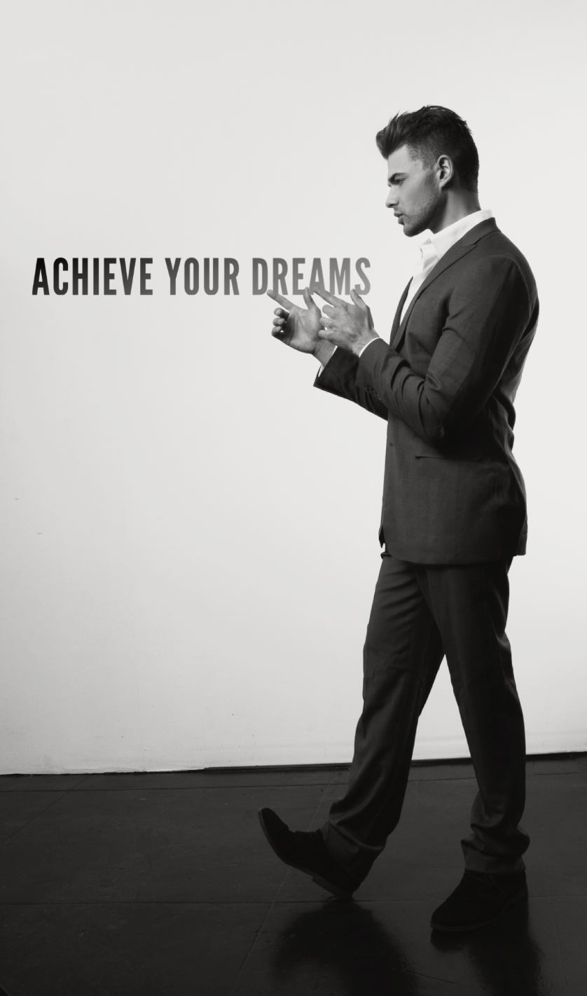 Kaden James in a suit pointing toward “Achieve Your Dreams” text, representing life coaching, goal setting, motivation, success, and personal transformation.