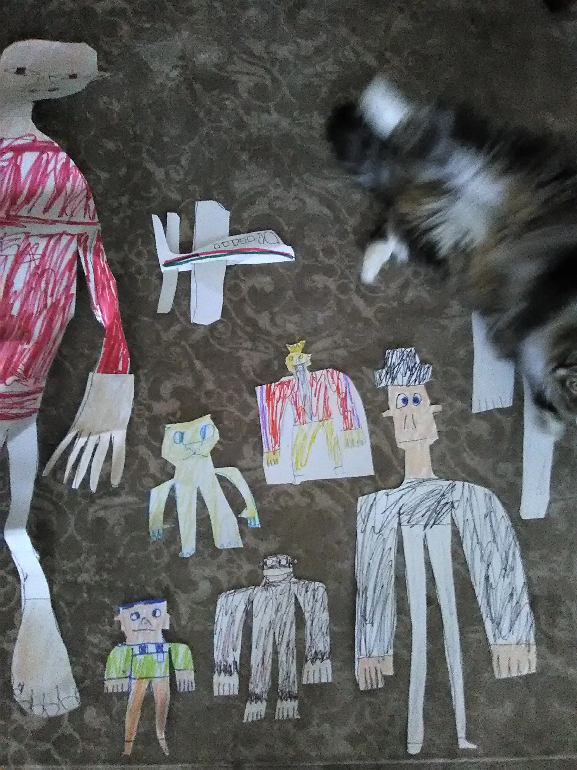 "PAPER DUDES" ARE CREATED WHOLE FROM A ROLL OF HEAVY CONSTRUCTION PAPER. NOTICE THE AIRPLANE, THE CAT AND THE APE. "MONSTER" THE CAT INSPECTS AT THE RIGHT.
