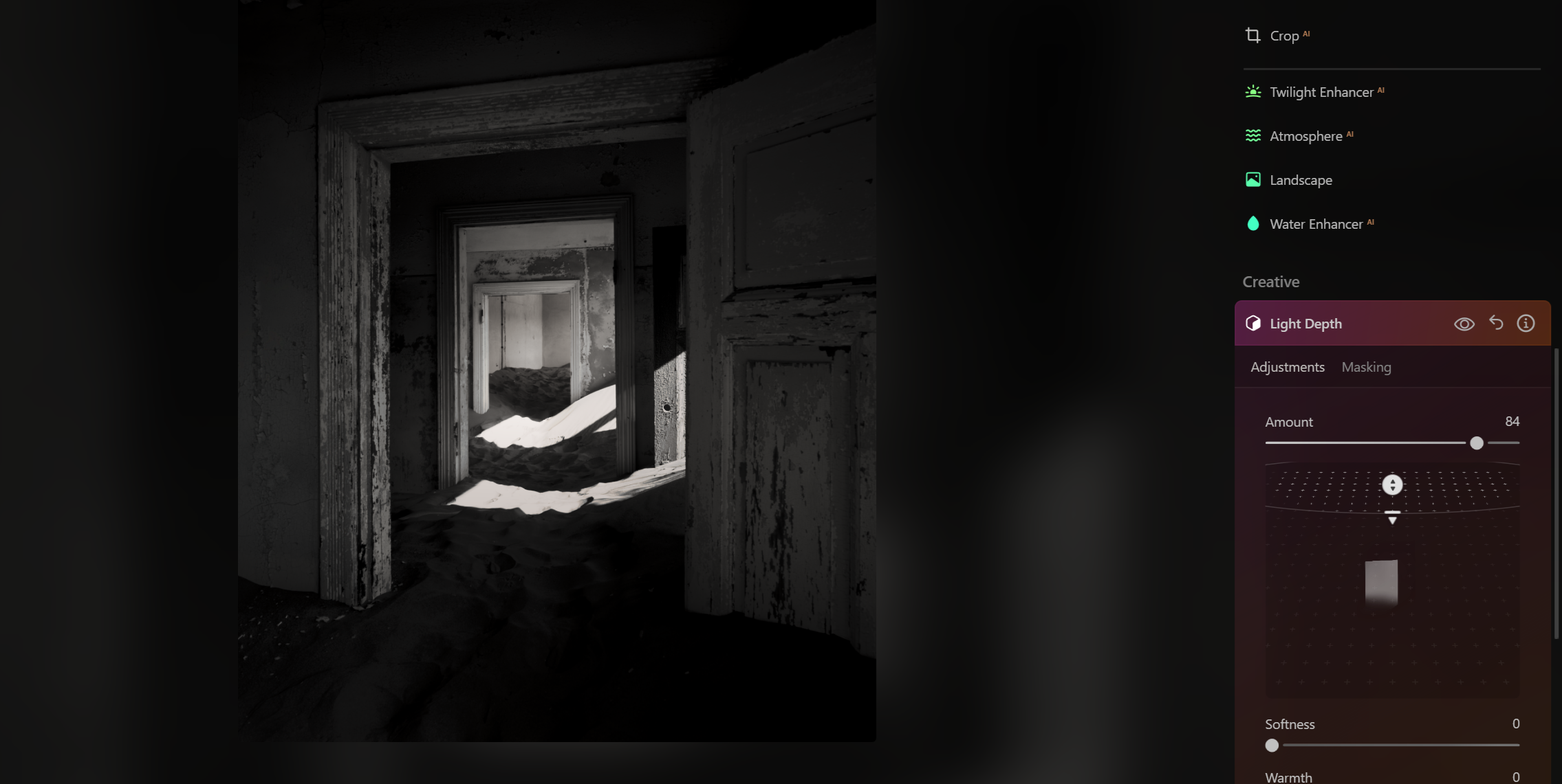 Black and white photo of an abandoned, dilapidated house with open doorways and sand dunes through the doors.