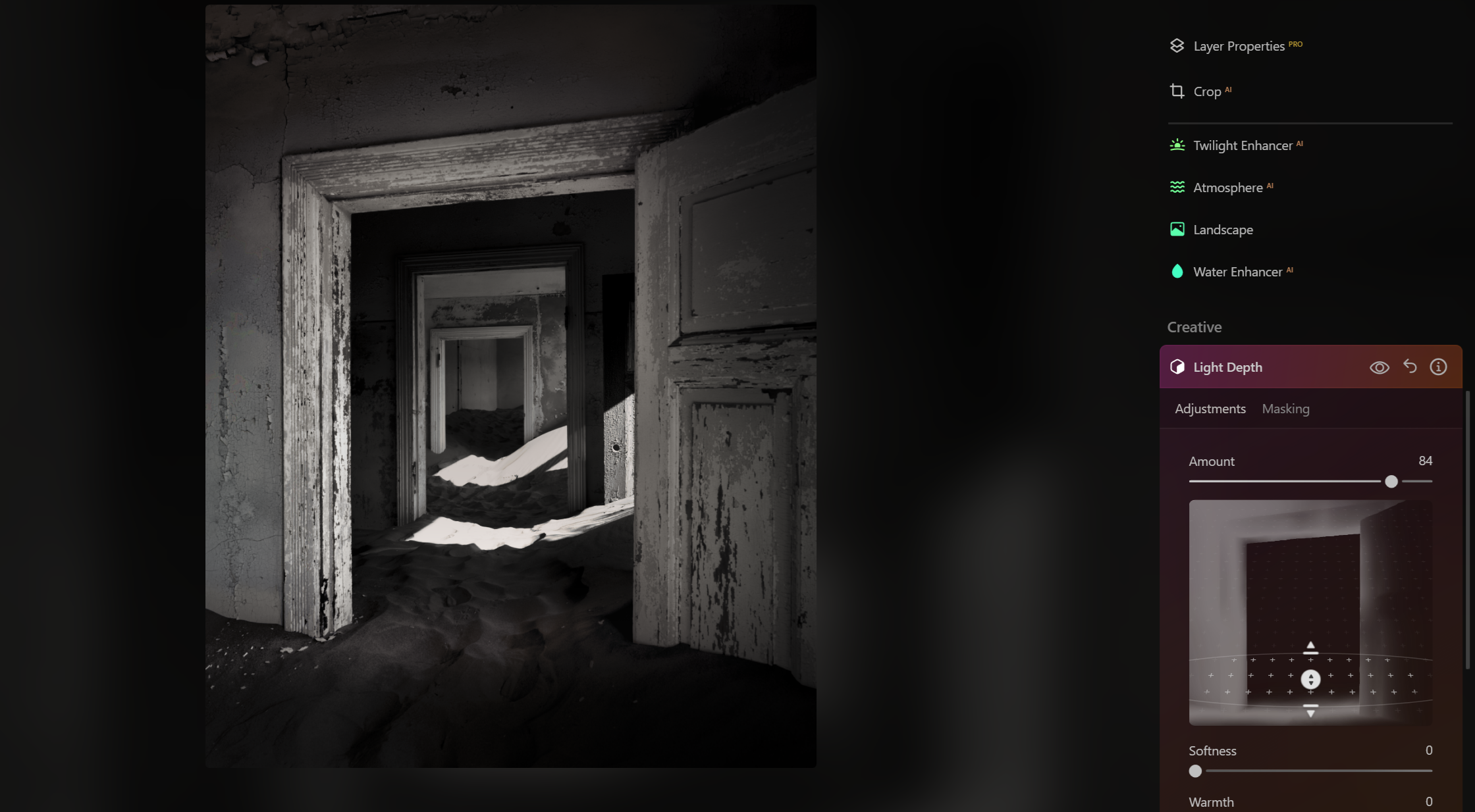 A black and white photo of an abandoned corridor inside a building with multiple doorways and dust on the floor.