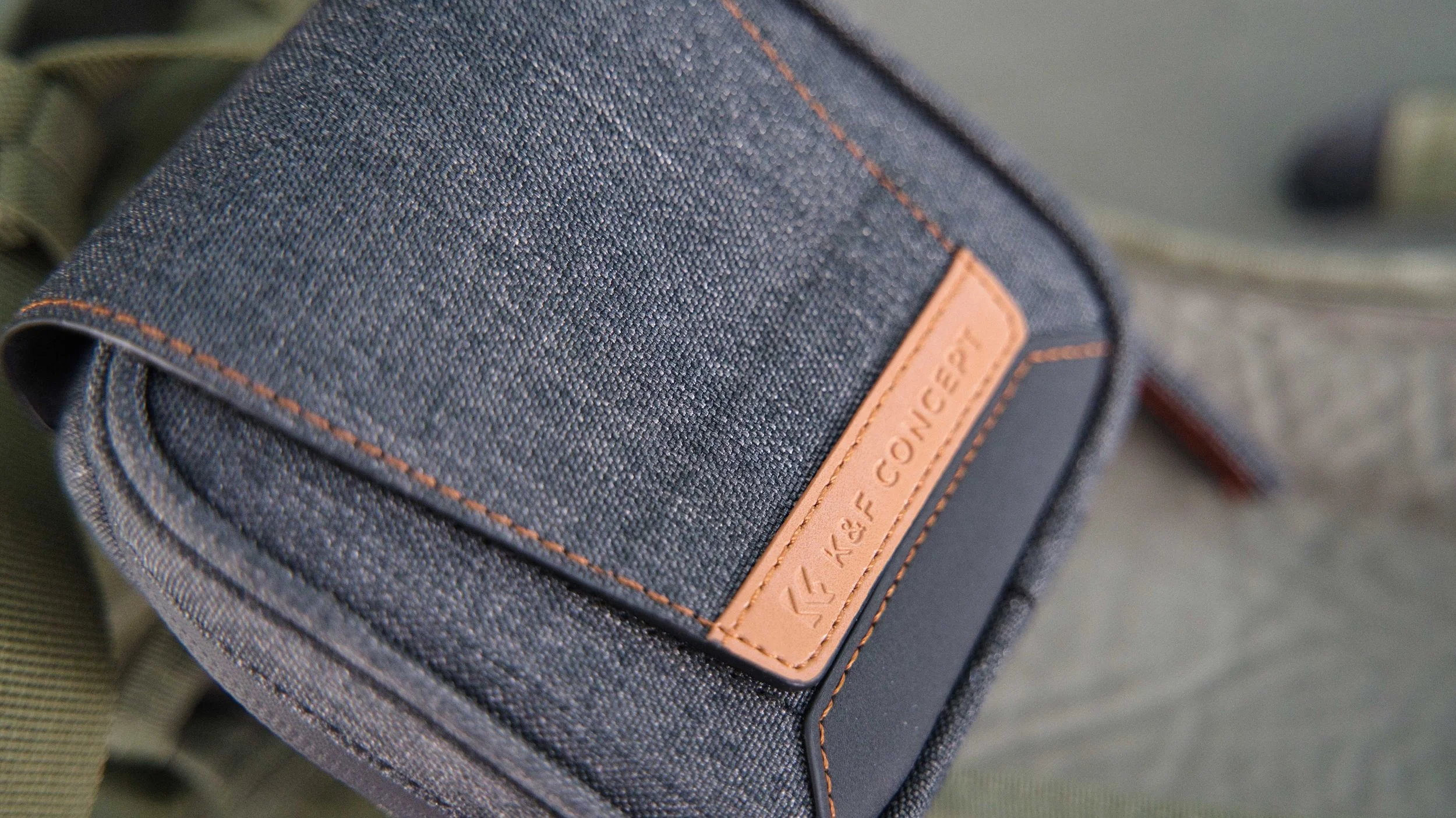 Close-up of a gray fabric camera bag with a leather patch labeled 'K&F CONCEPT'.