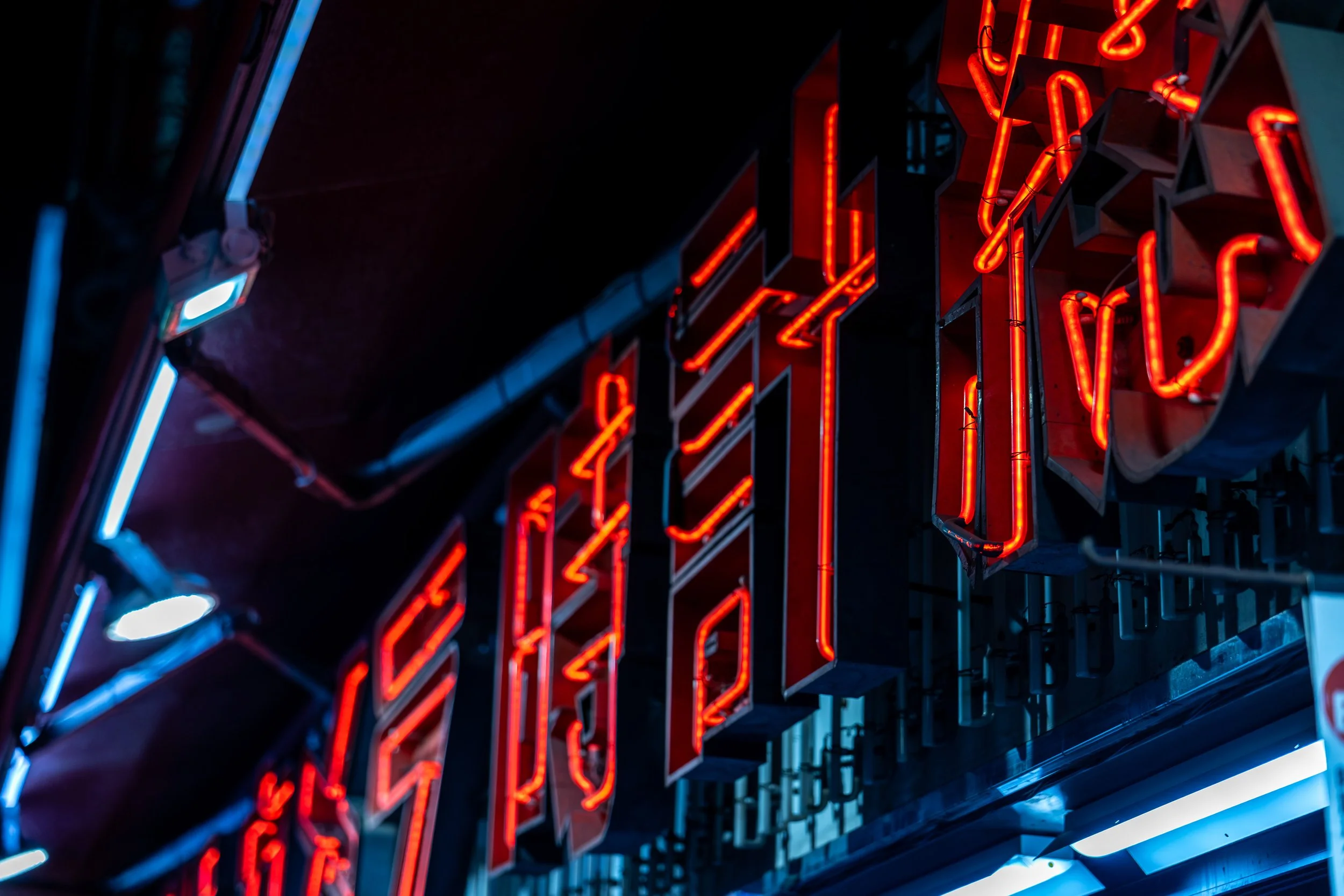 Close-up of a neon sign with red glowing letters against a dark background.