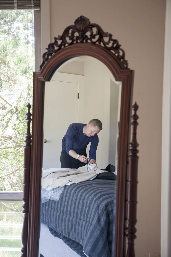 Mirrored image of the groom fixing up his suit coat