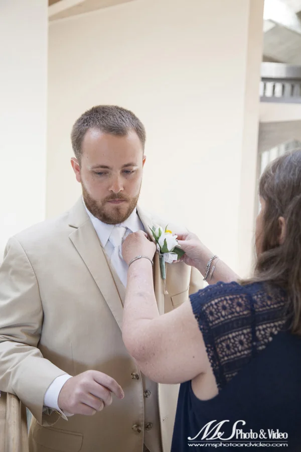 The groom getting the corsage pinned on