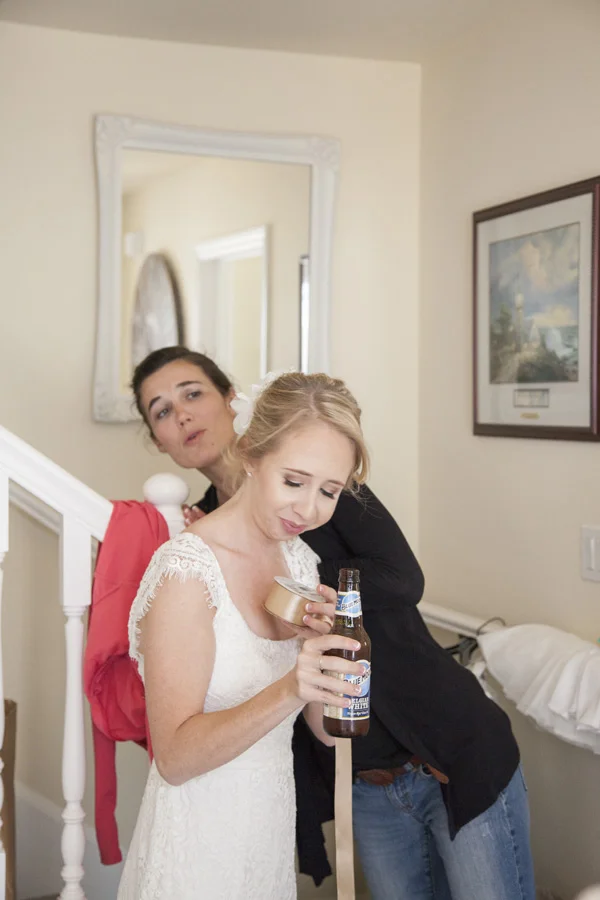 Bride getting a quick drink as her friends inspects her hair