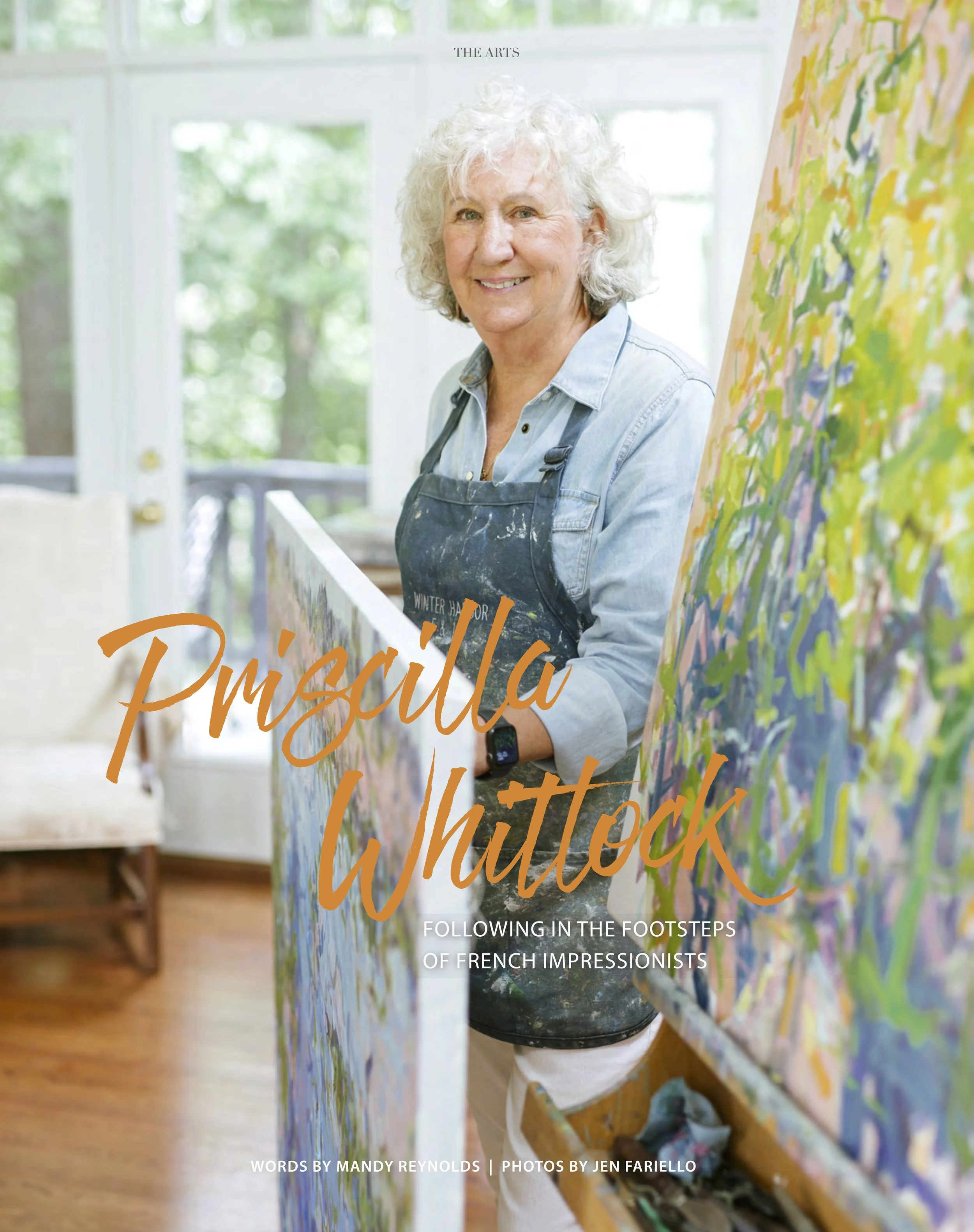 Priscilla standing in front of a large, colorful abstract painting in an art studio with large windows in the background.