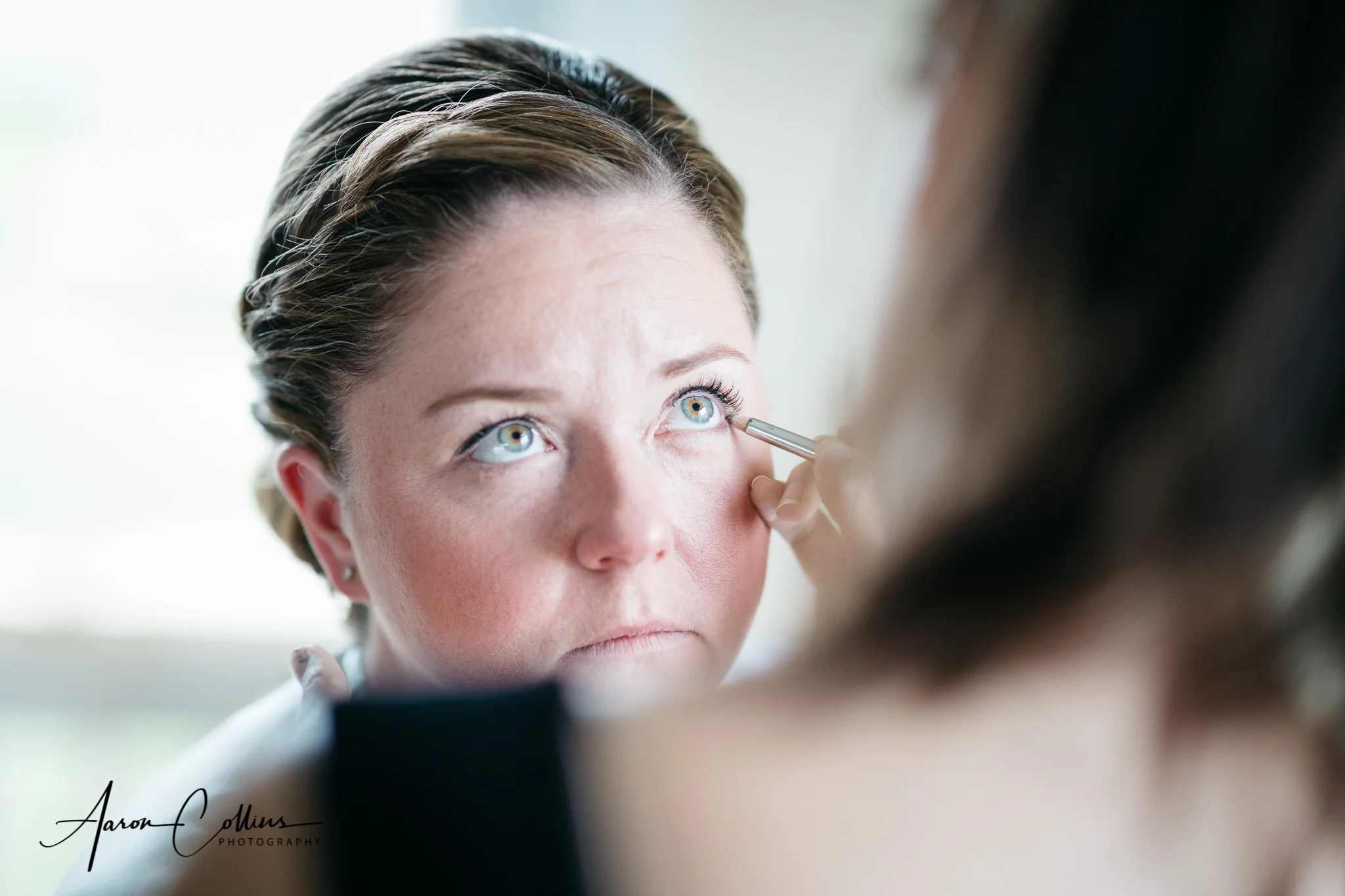 Bride getting eyeliner applied by Lisa George during preparations.