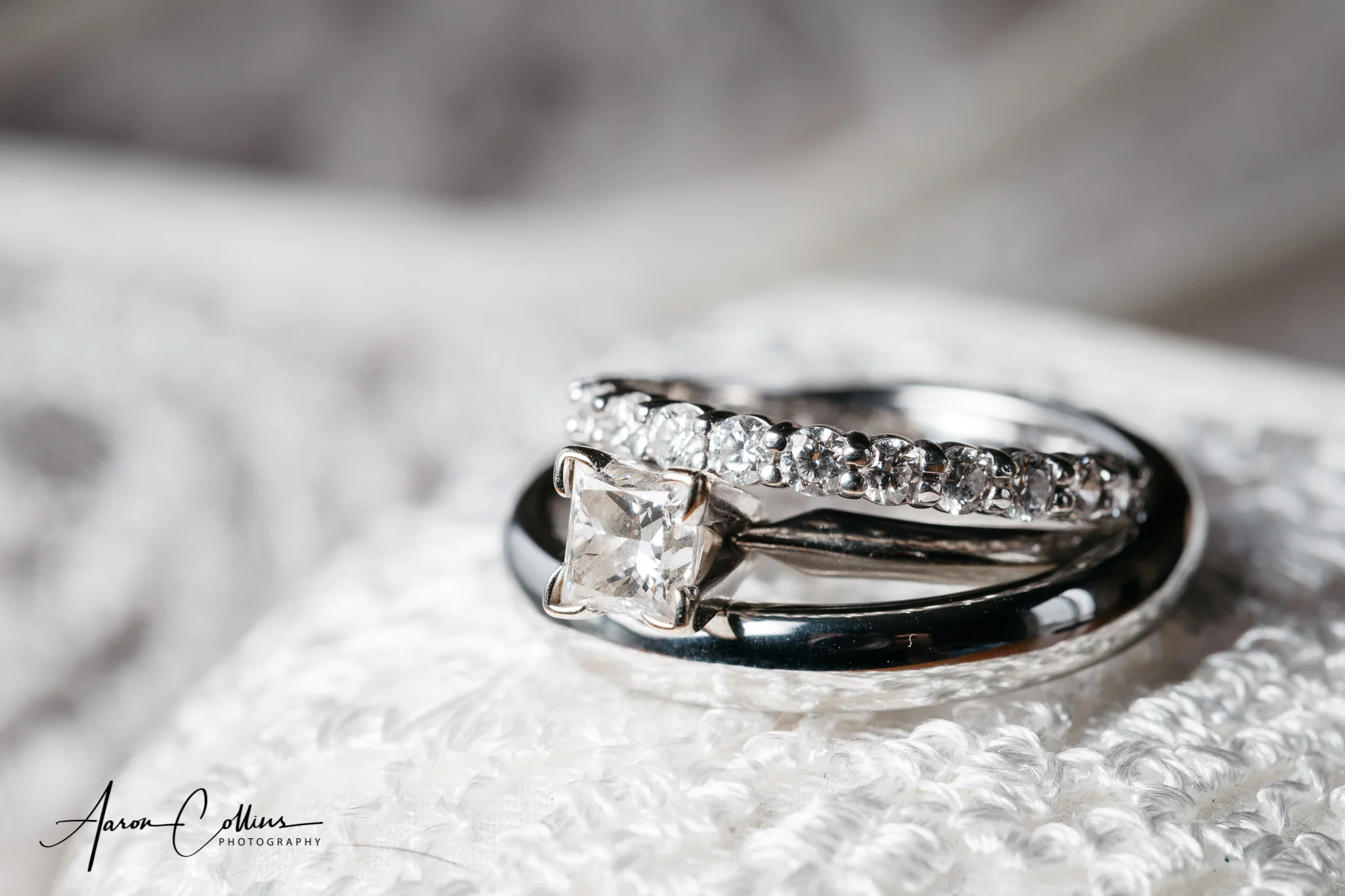 The wedding rings and diamond engagement ring close-up on top of the bride's white shoes.