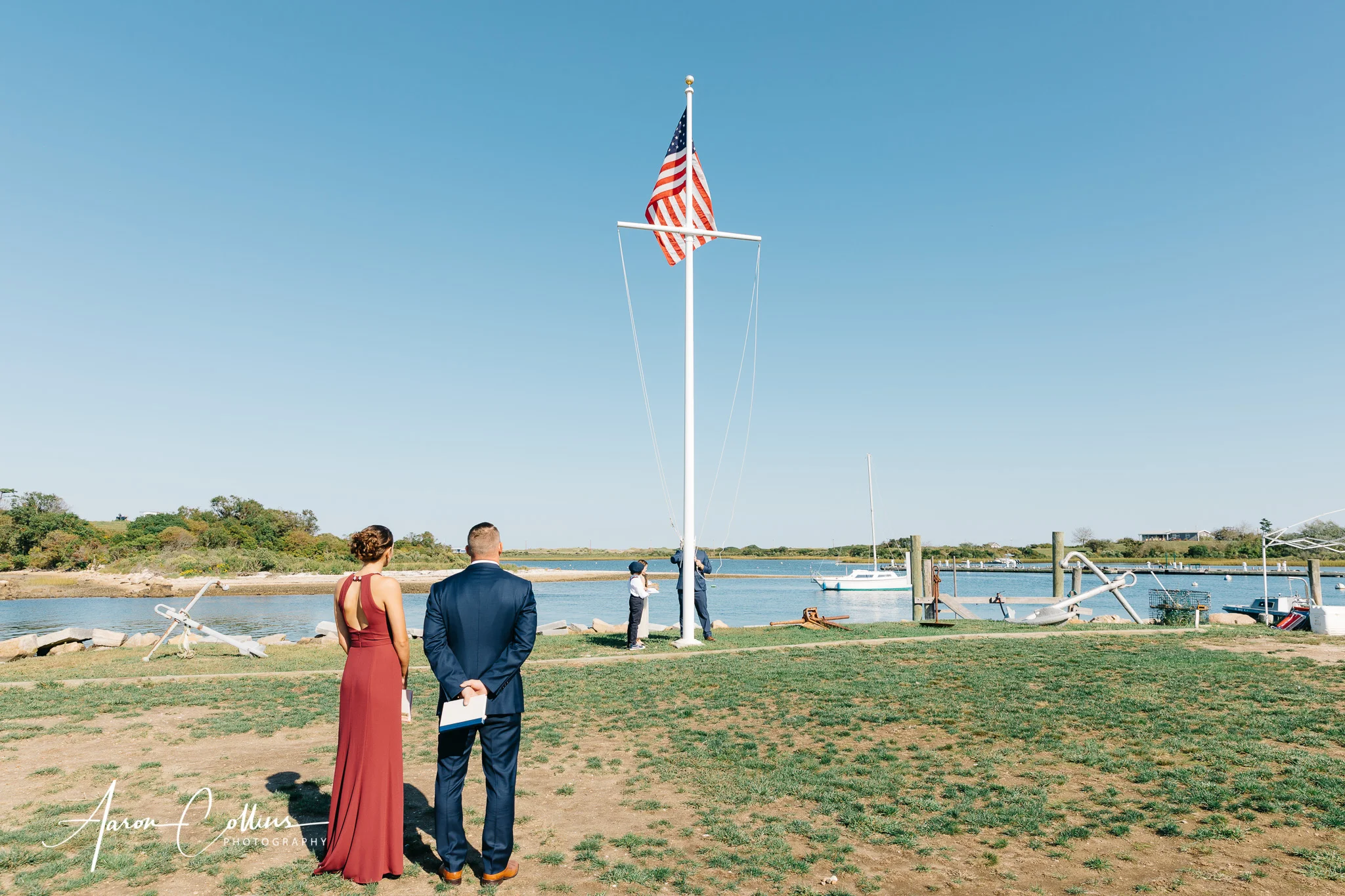 Flag is raised before the wedding ceremony begins with New Harbor Block Island and a few boats and other nautical gear visible in the background