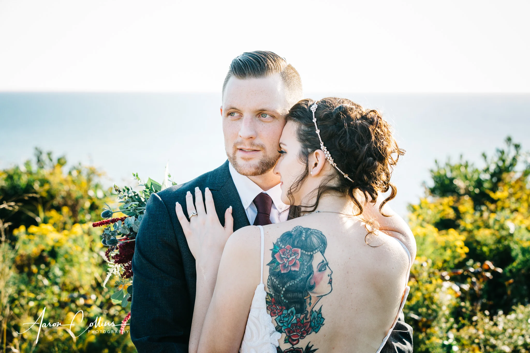 Bride facing Groom at Mohegan Bluffs on Block Island with her back tattoo visible and Block Island Sound visible in the background