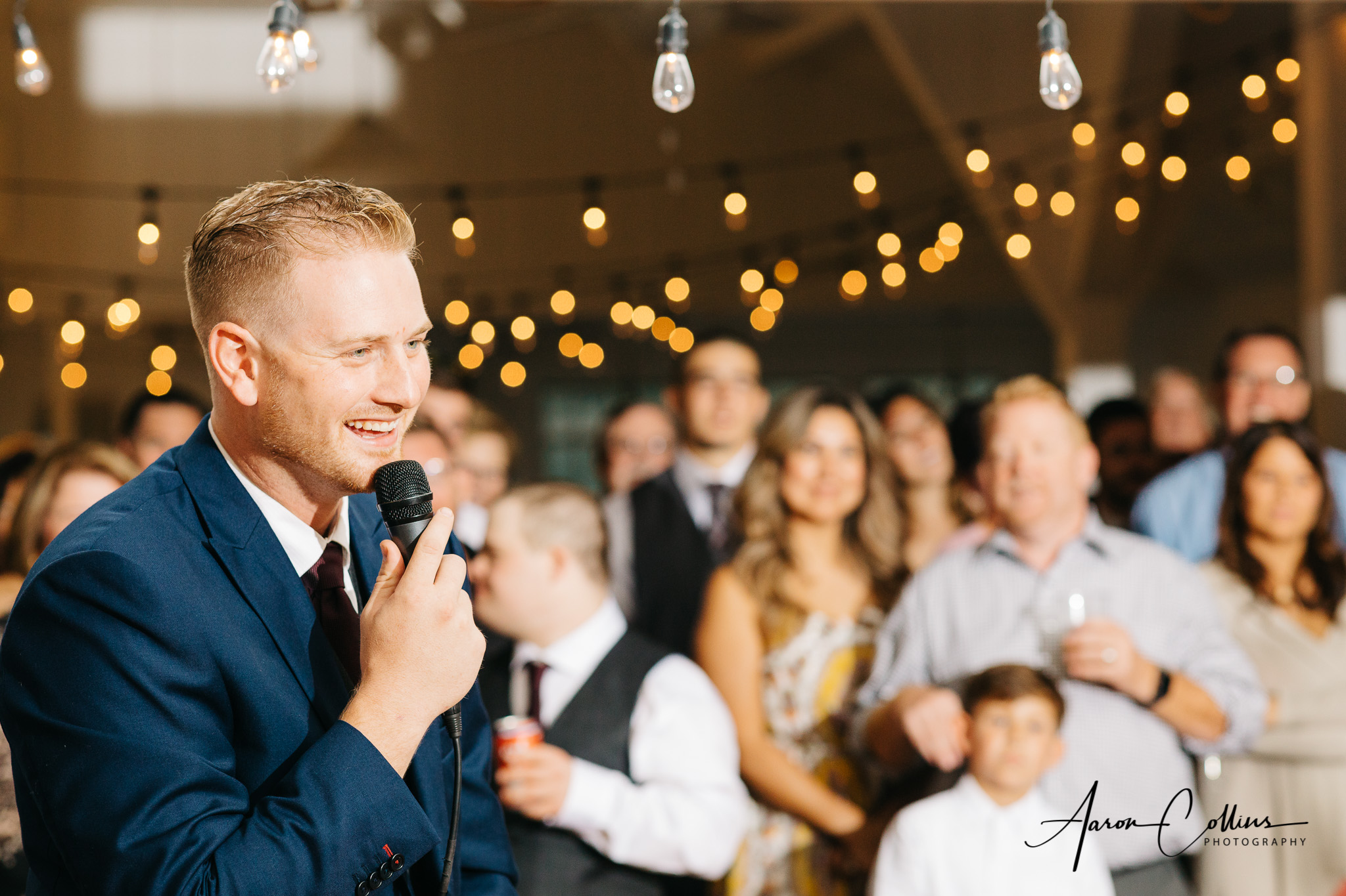 Best man giving the speech at Block Island Maritime Institute with bokeh visible in the lighting hanging in the background