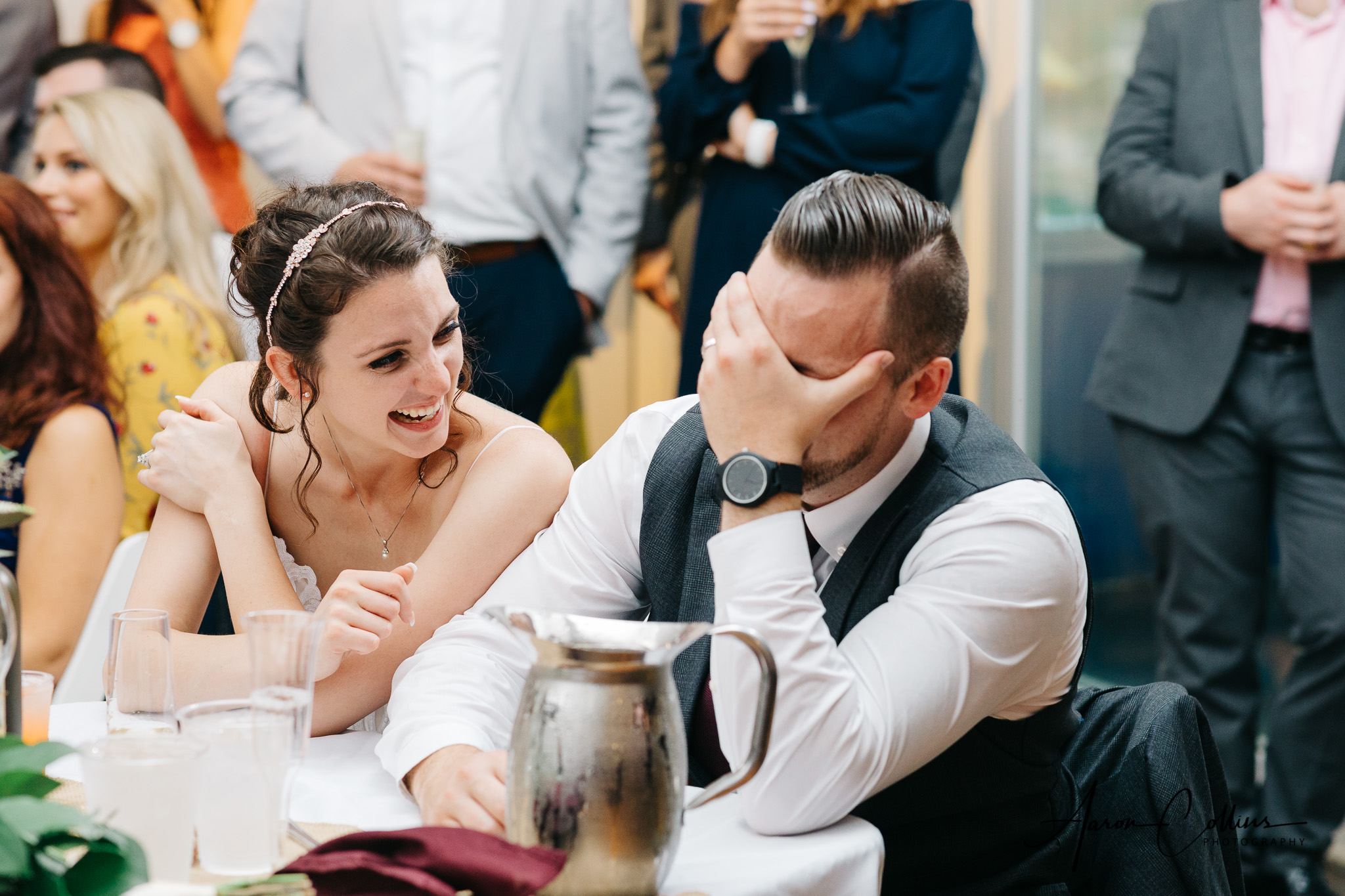Groom covering his face reacting to the toast from best man while bride laughs at Block Island Maritime Institute
