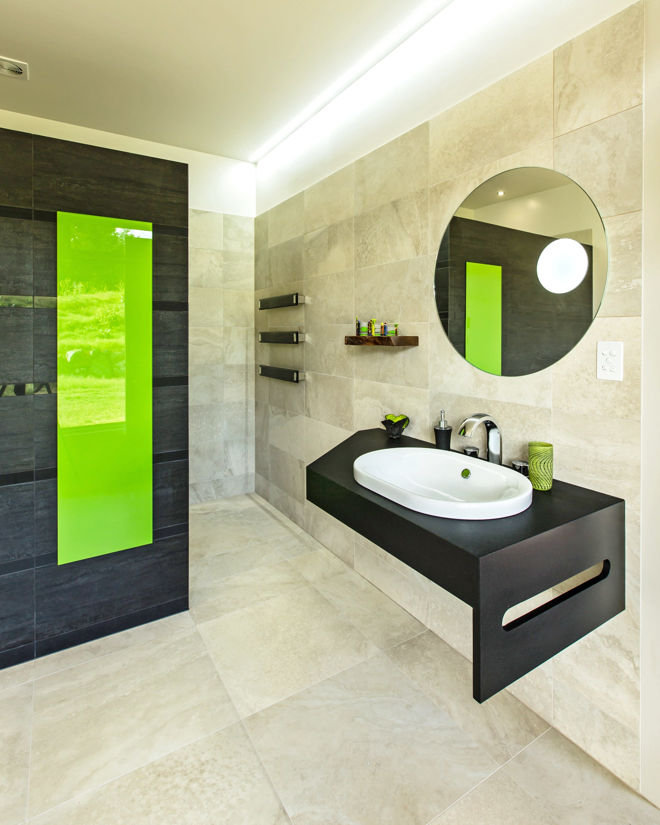 Round bathroom mirror in tiled wall with dark vanity