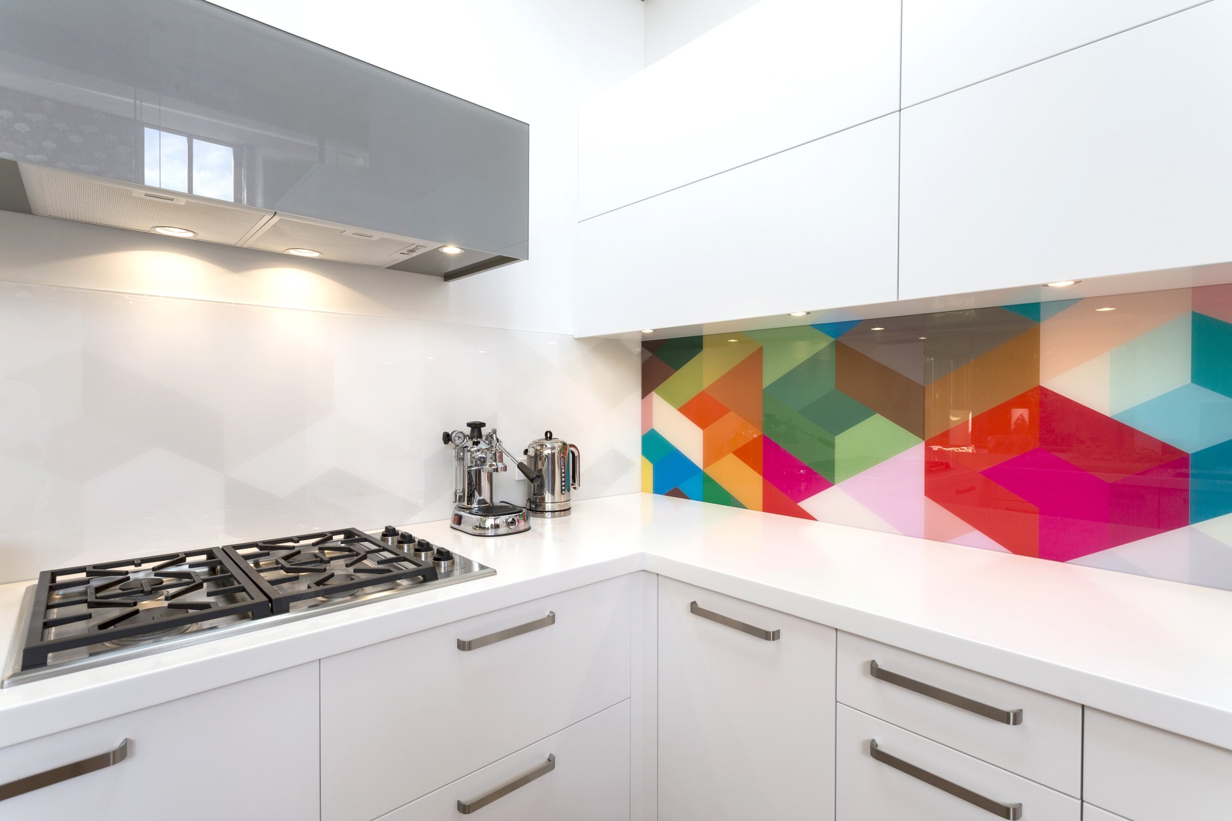 Geometric glass art splashback in modern white kitchen