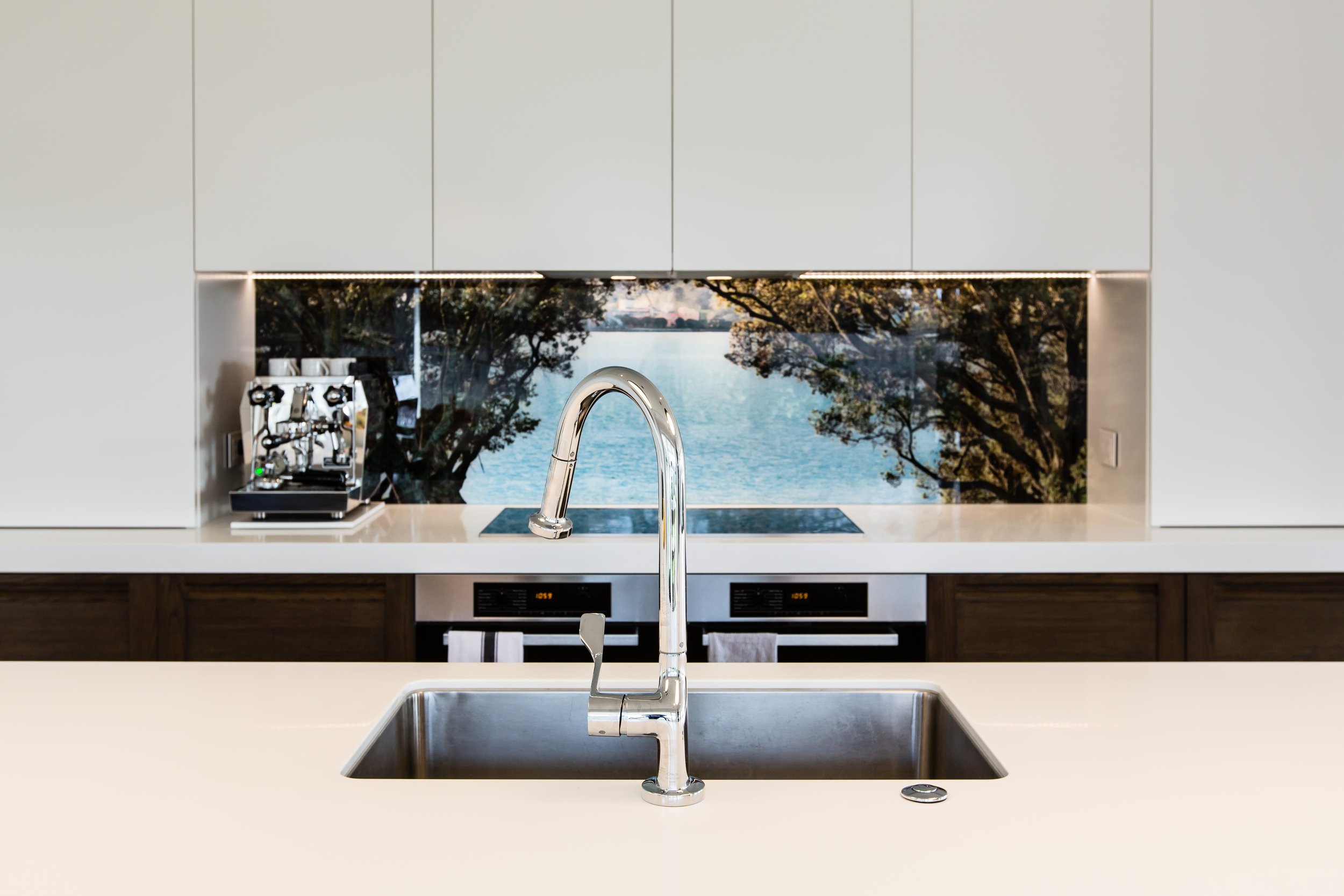 White kitchen with glass art printed splashback with water view