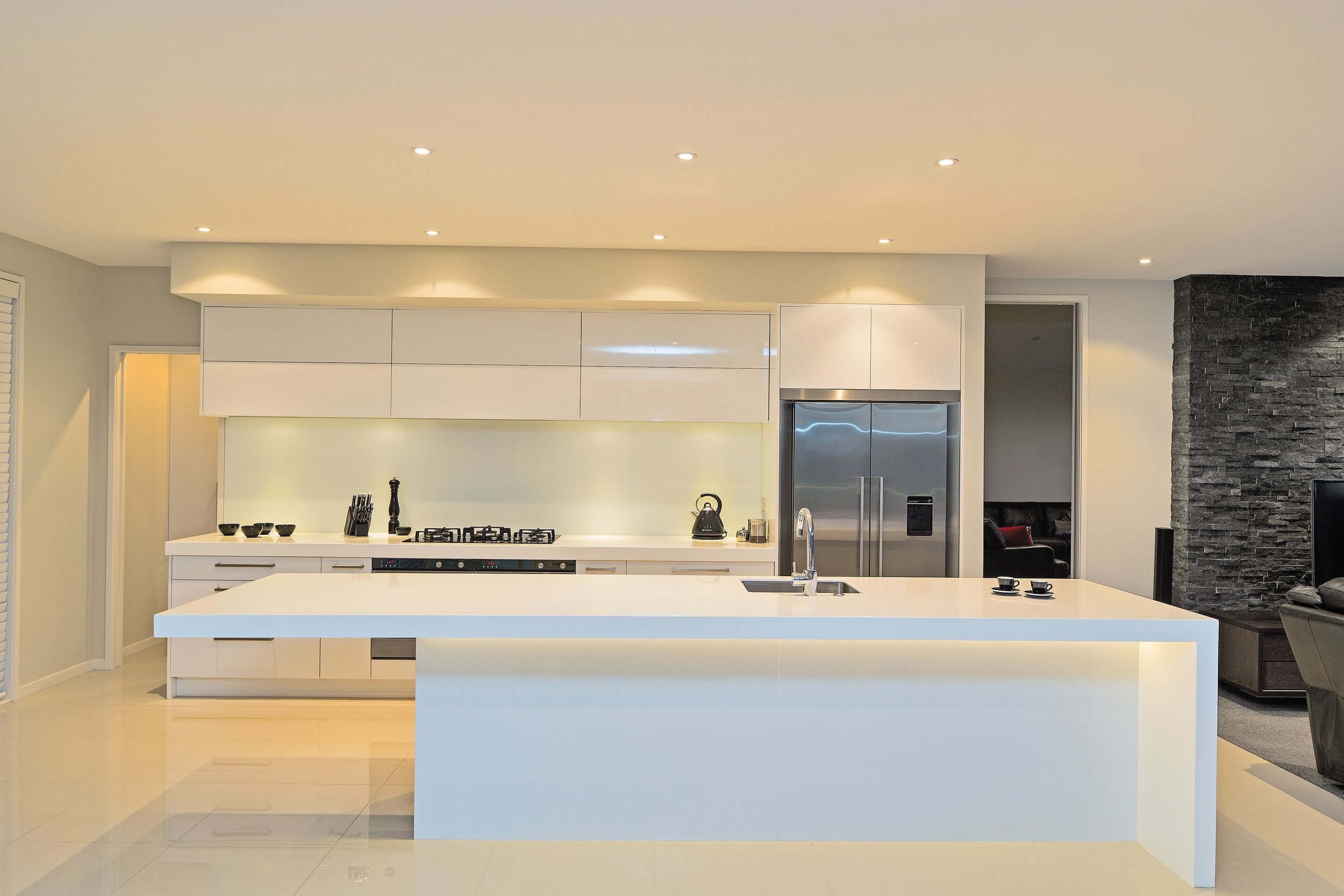 Galley kitchen with hi gloss cabinetry and off white glass splashback with shimmer