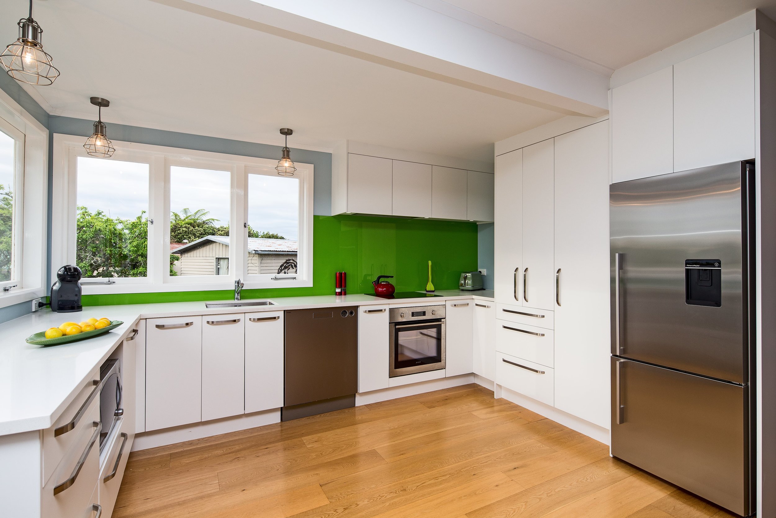 Modern white kitchen with feature green glass splashback