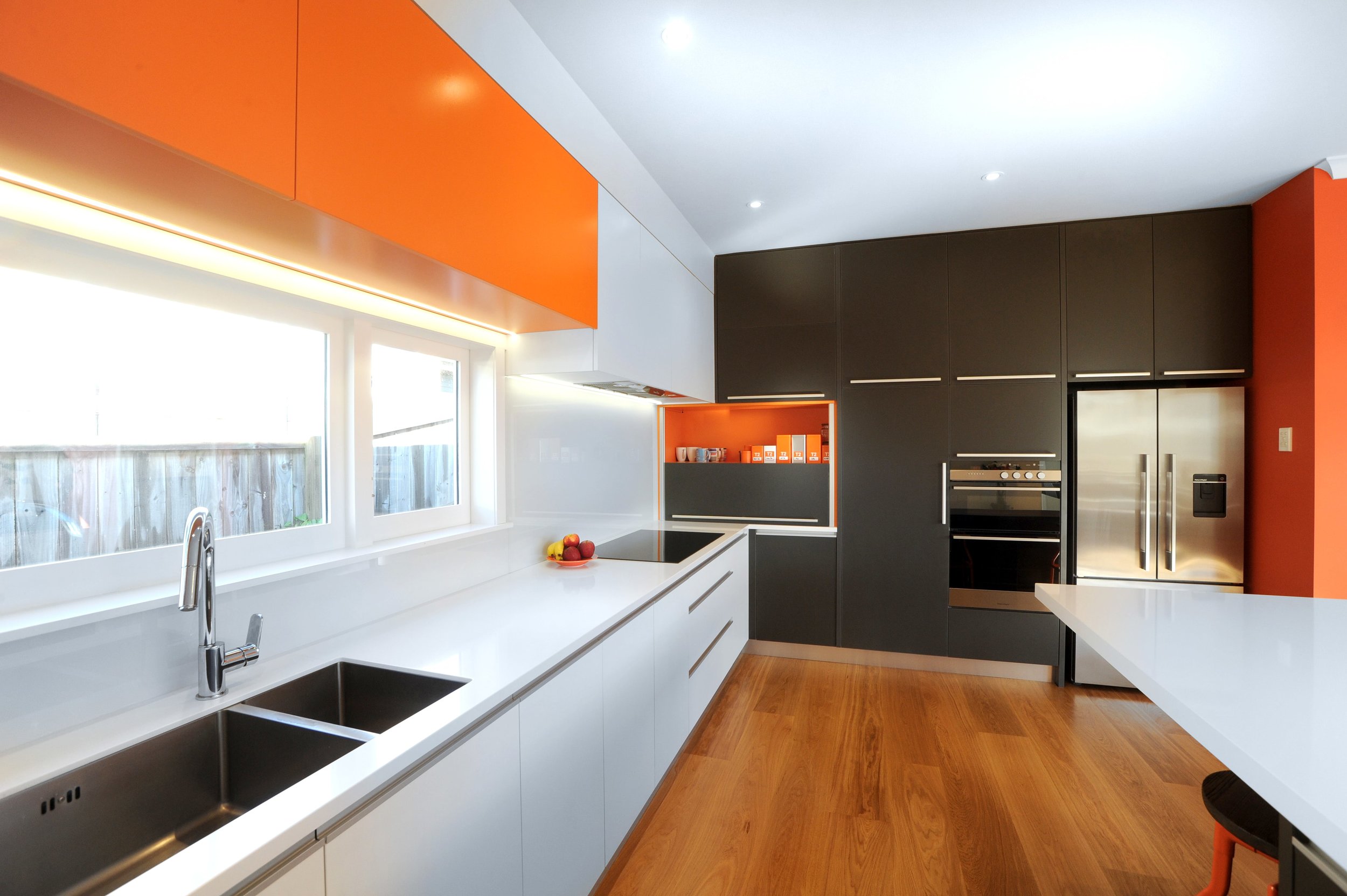 Colourful galley kitchen with white benchtop and white backpainted glass splashback